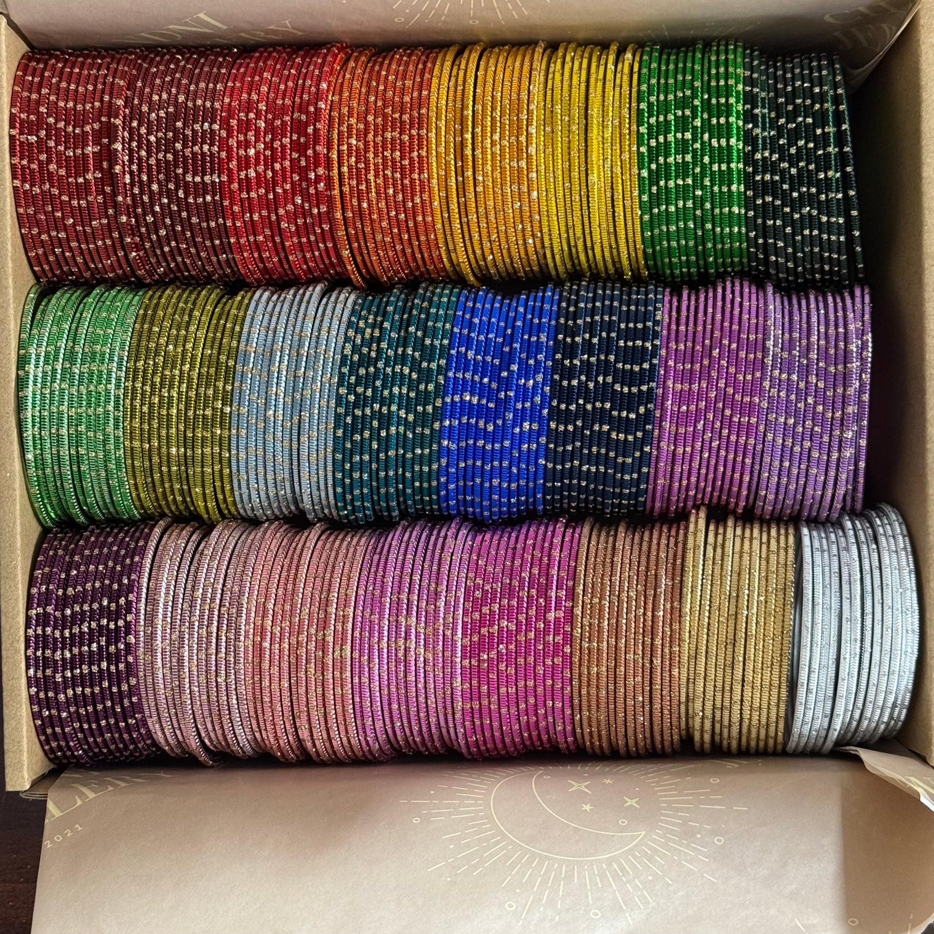 Box containing colorful bangles stacked in rows.