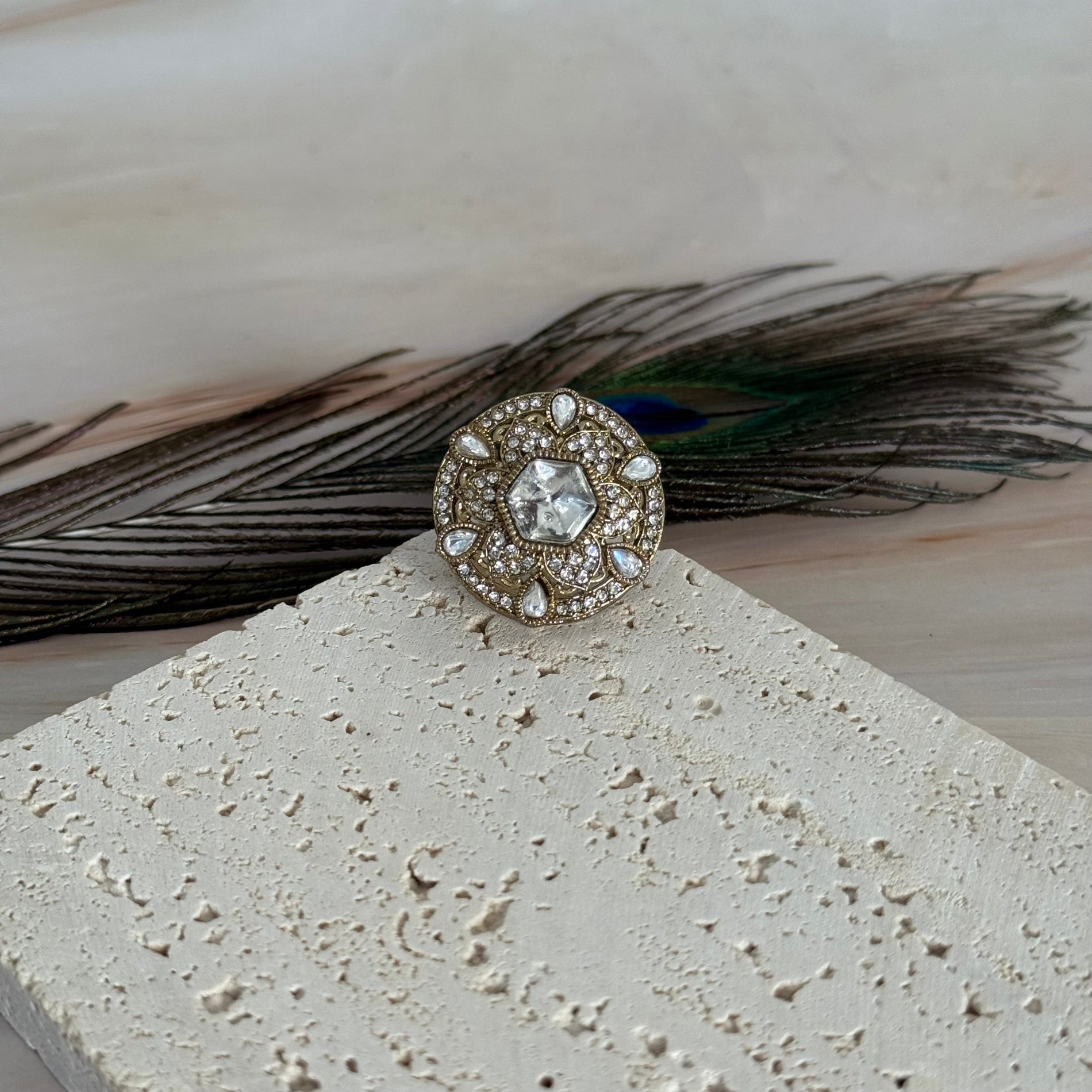 Decorative ring with gemstone and feathers on a textured surface
