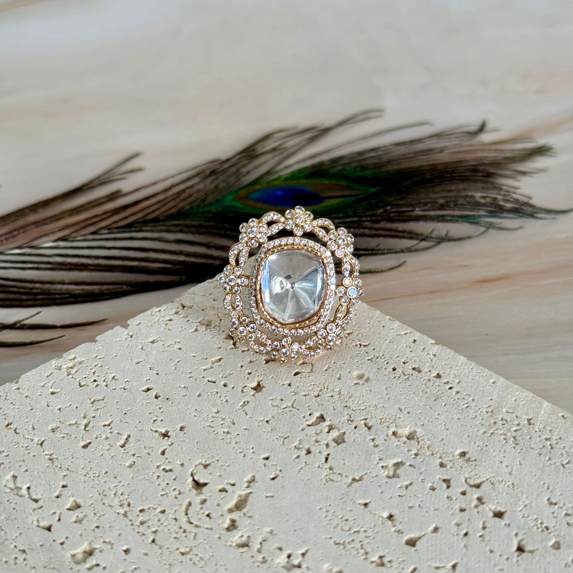 Decorative ring with peacock feather on a textured surface