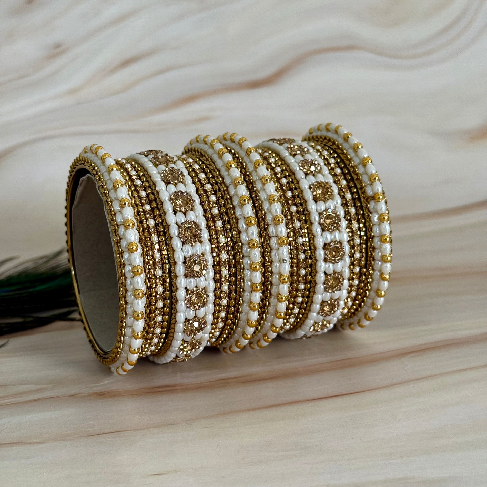 Set of gold and white beaded bangles on a wooden surface