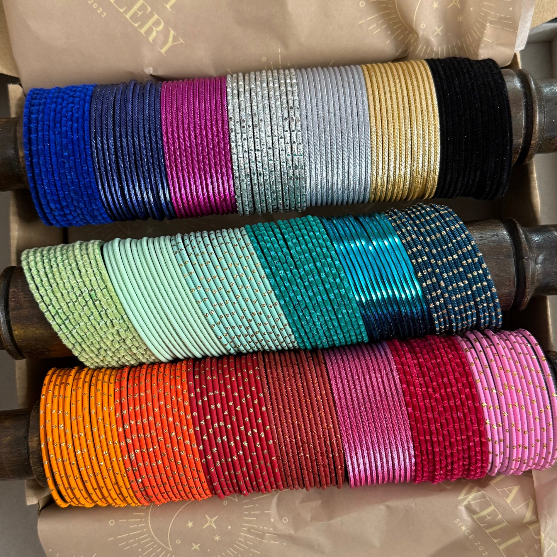 Colorful bangles on a metal rack with a brand name visible.