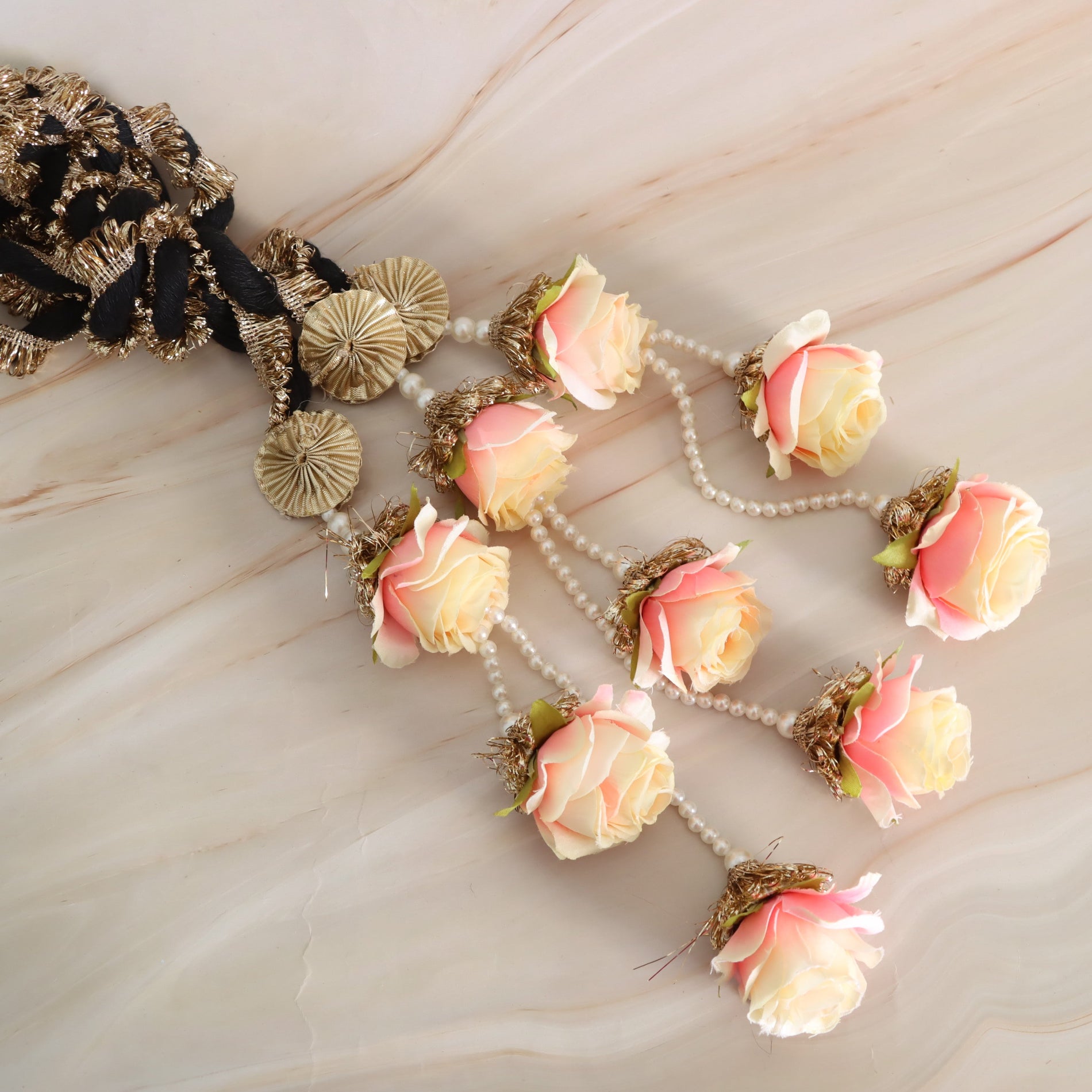 Decorative headband with pink and yellow flowers and gold accents on a marble surface