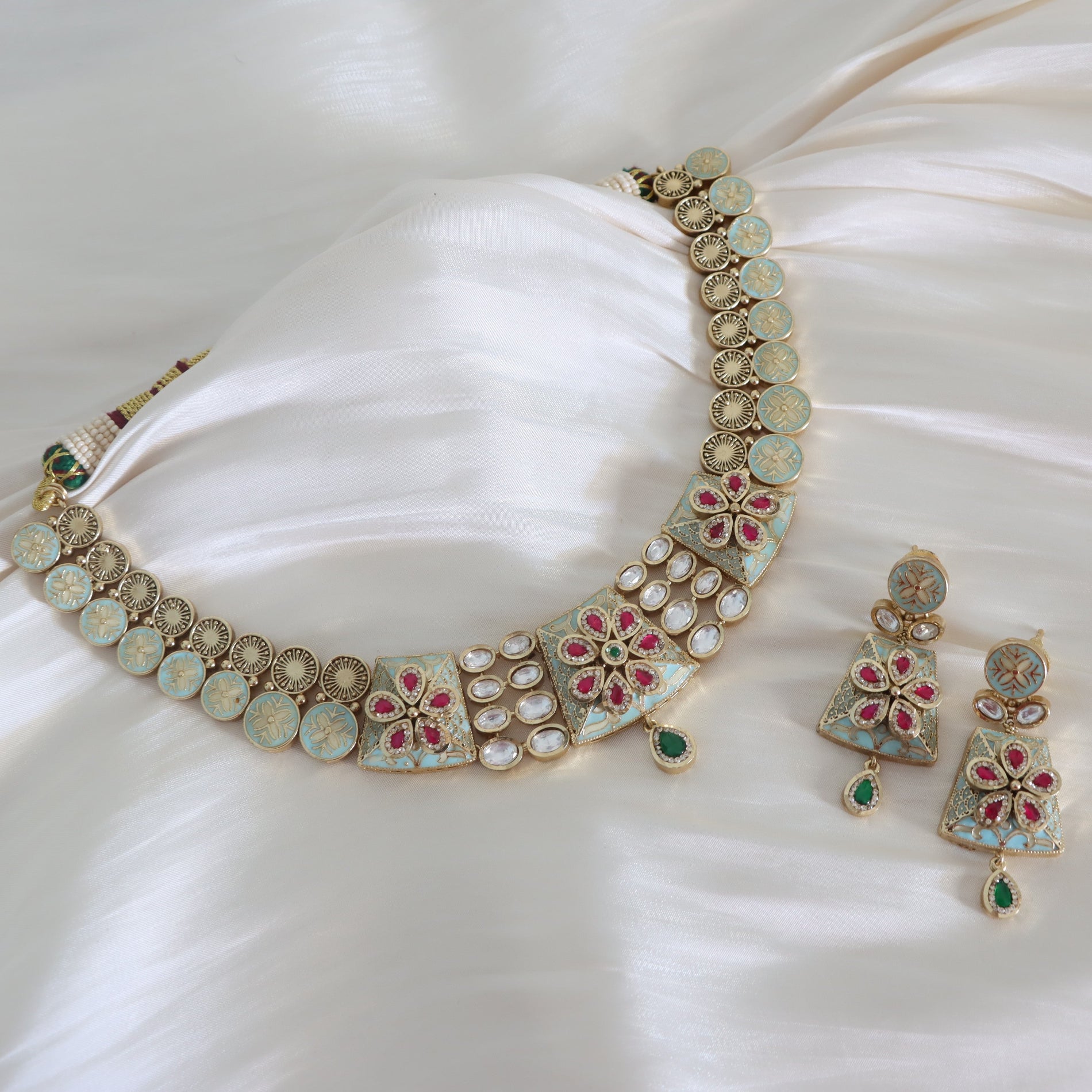 Ornate necklace and earrings set on a white fabric background