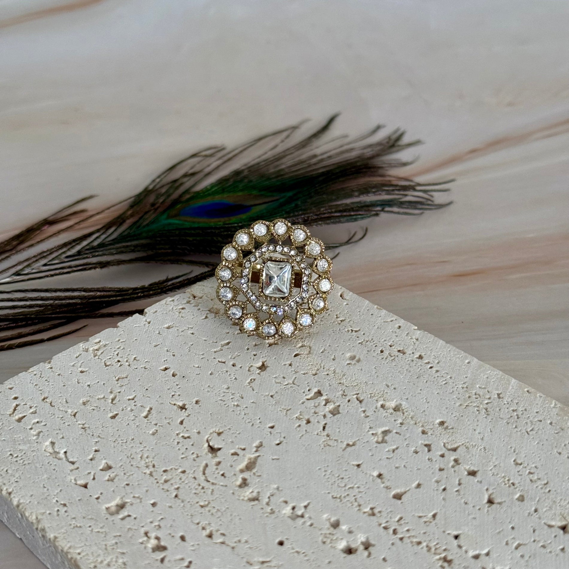 Decorative ring with peacock feather on a textured surface