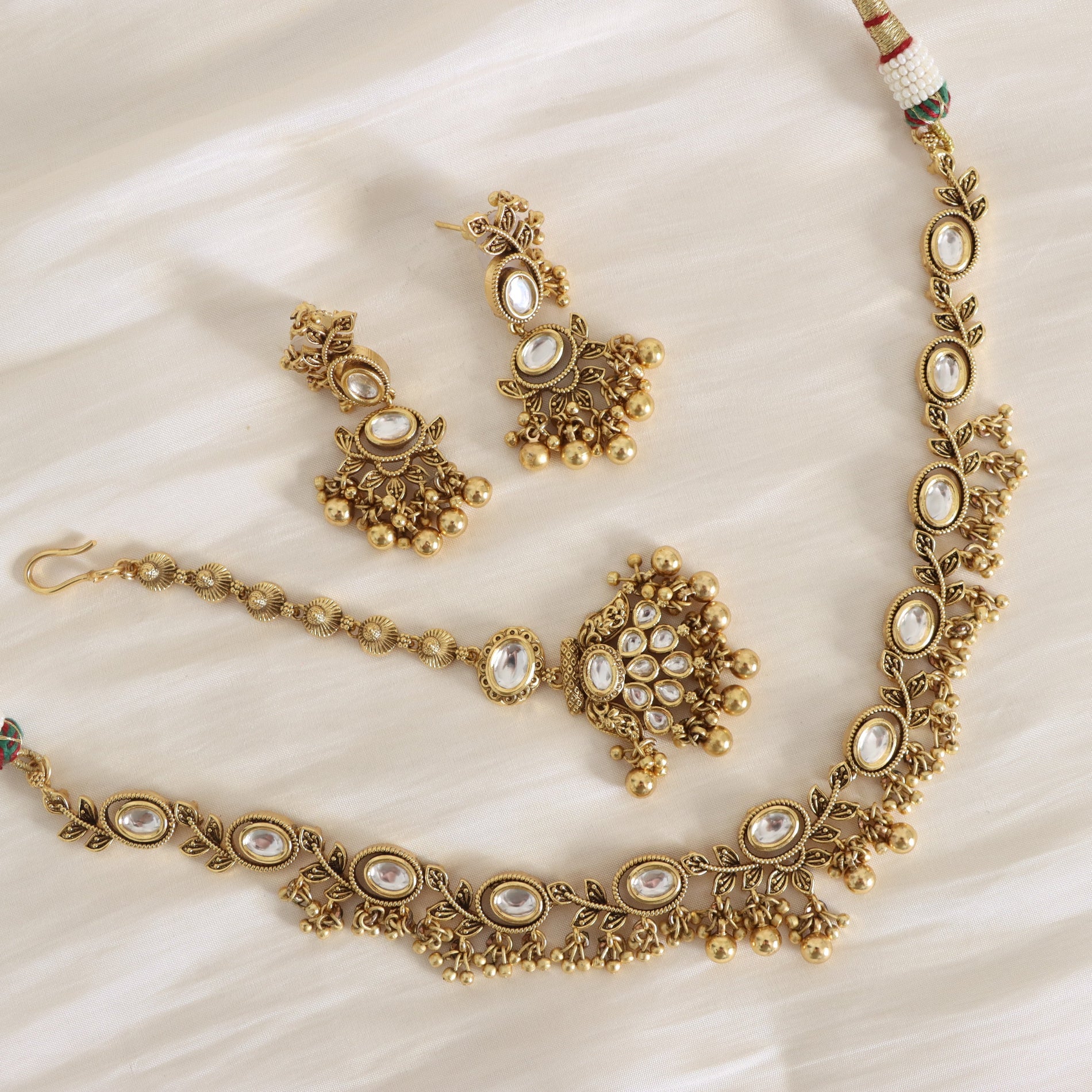 Gold jewelry set with necklace, earrings, and bracelet on a white fabric background
