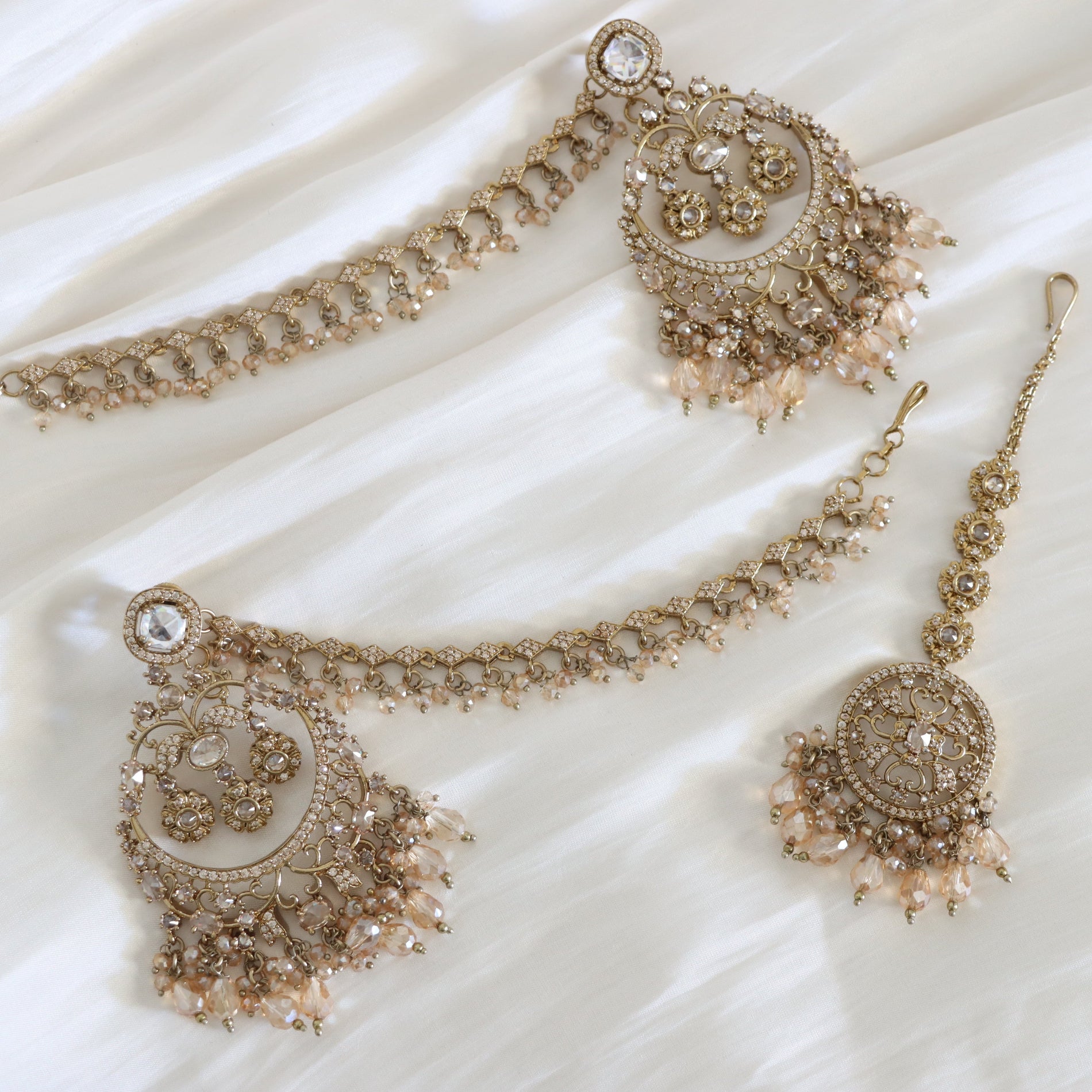 Ornate gold jewelry set on a white fabric background