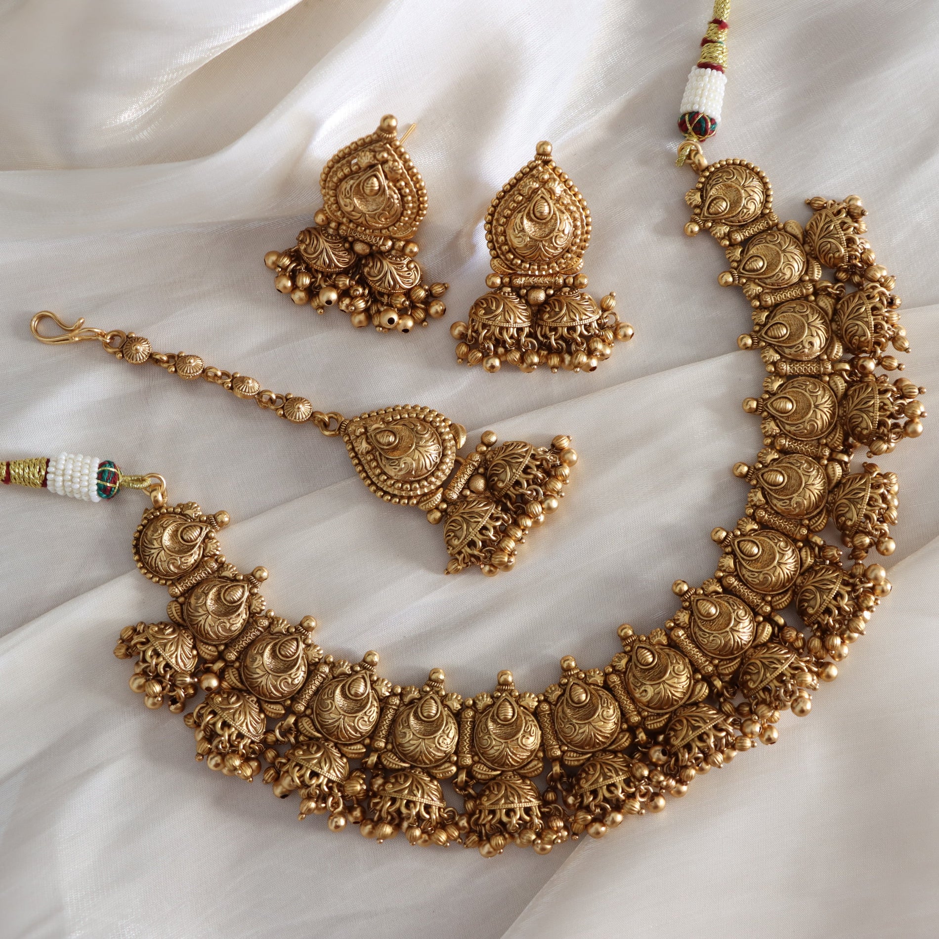 Gold necklace and earrings set on a white fabric background