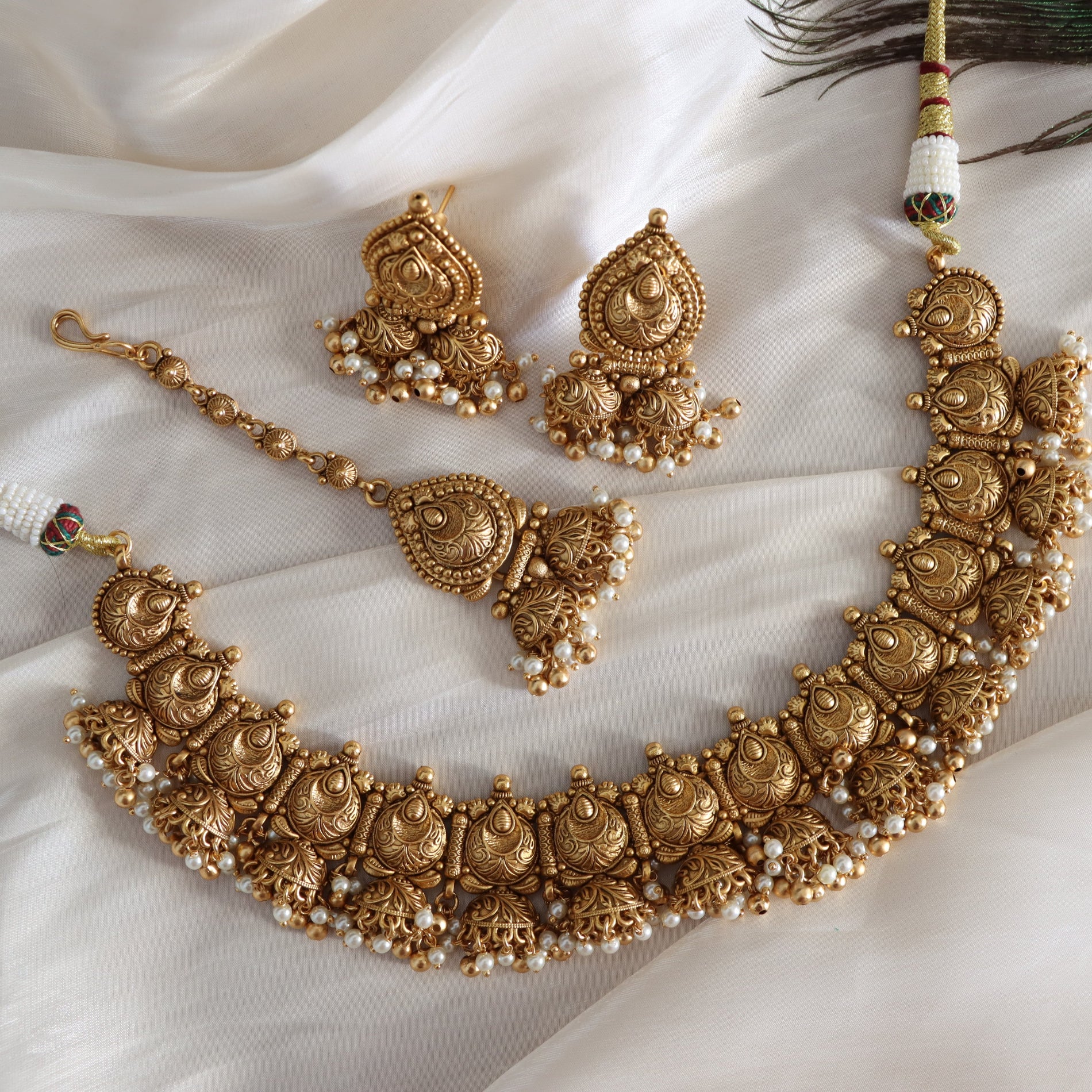 Gold necklace and earrings set on a white fabric background