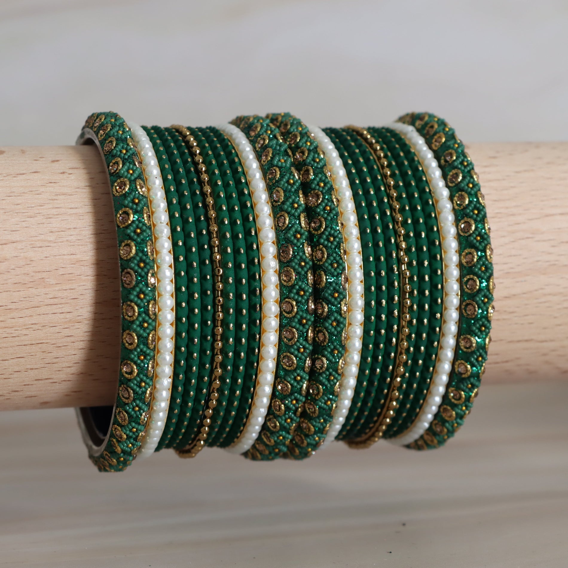 Set of green and white beaded bangles on a wooden rod