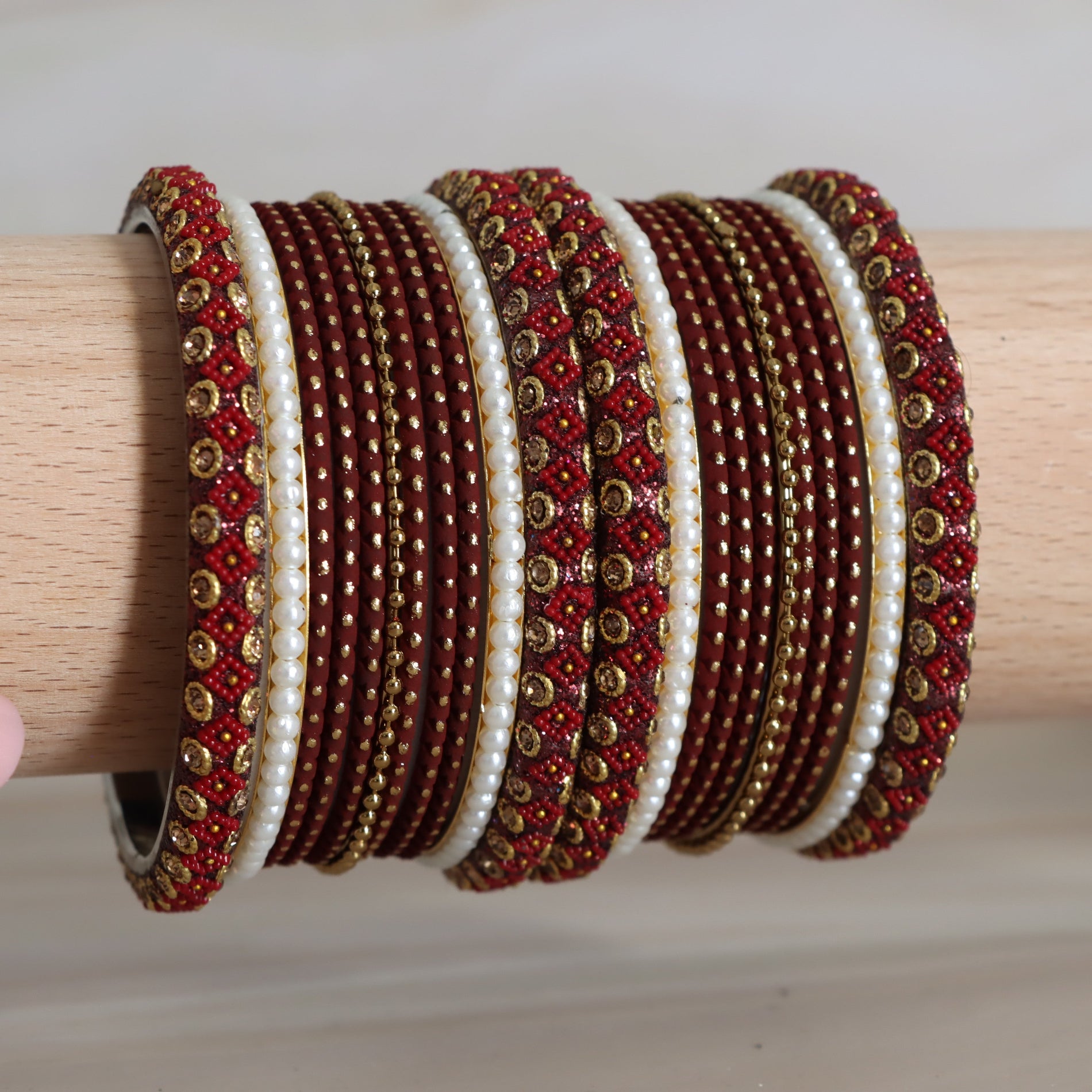 Set of red, gold, and white beaded bracelets on a wooden stick.