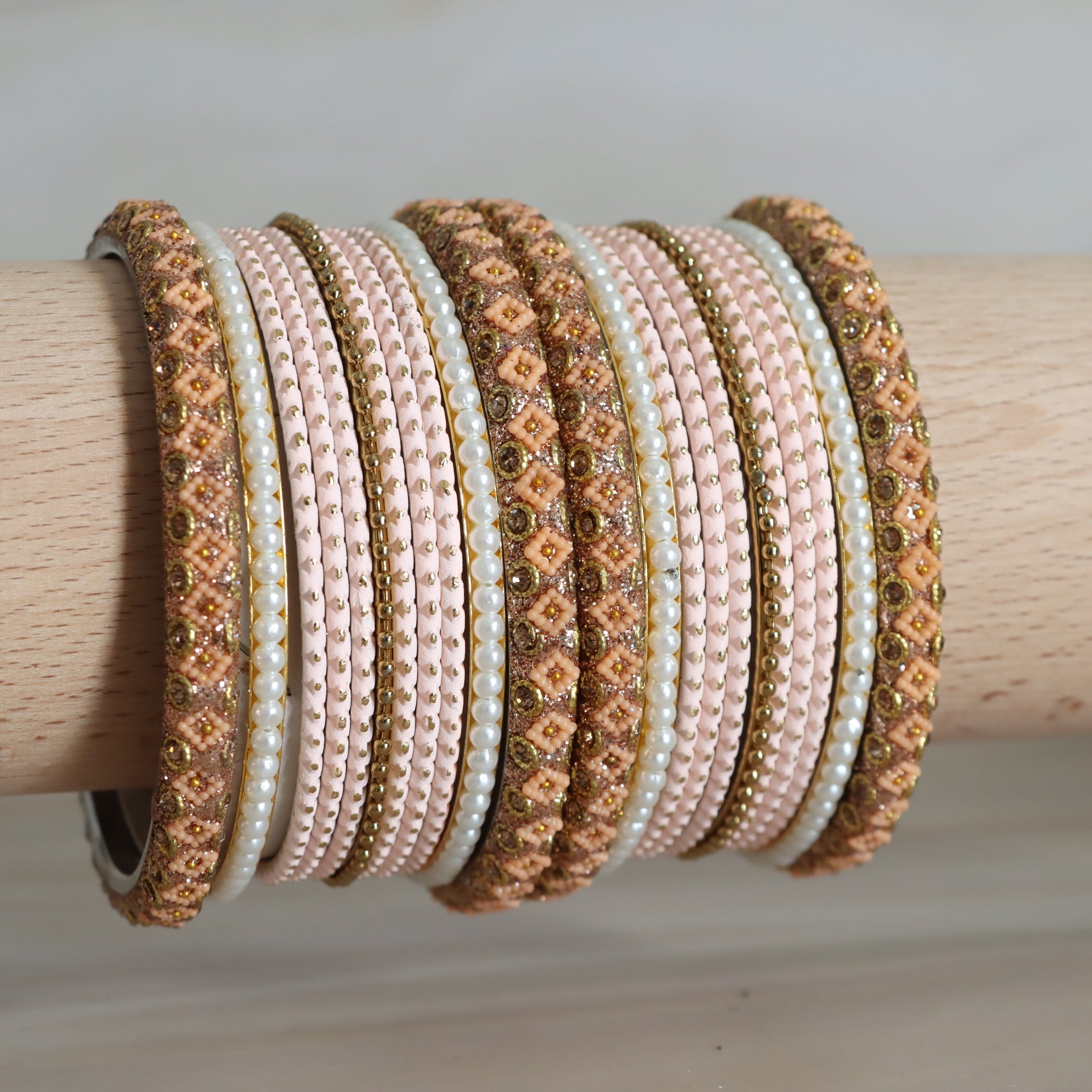 Set of decorative bracelets on a wooden rod against a neutral background