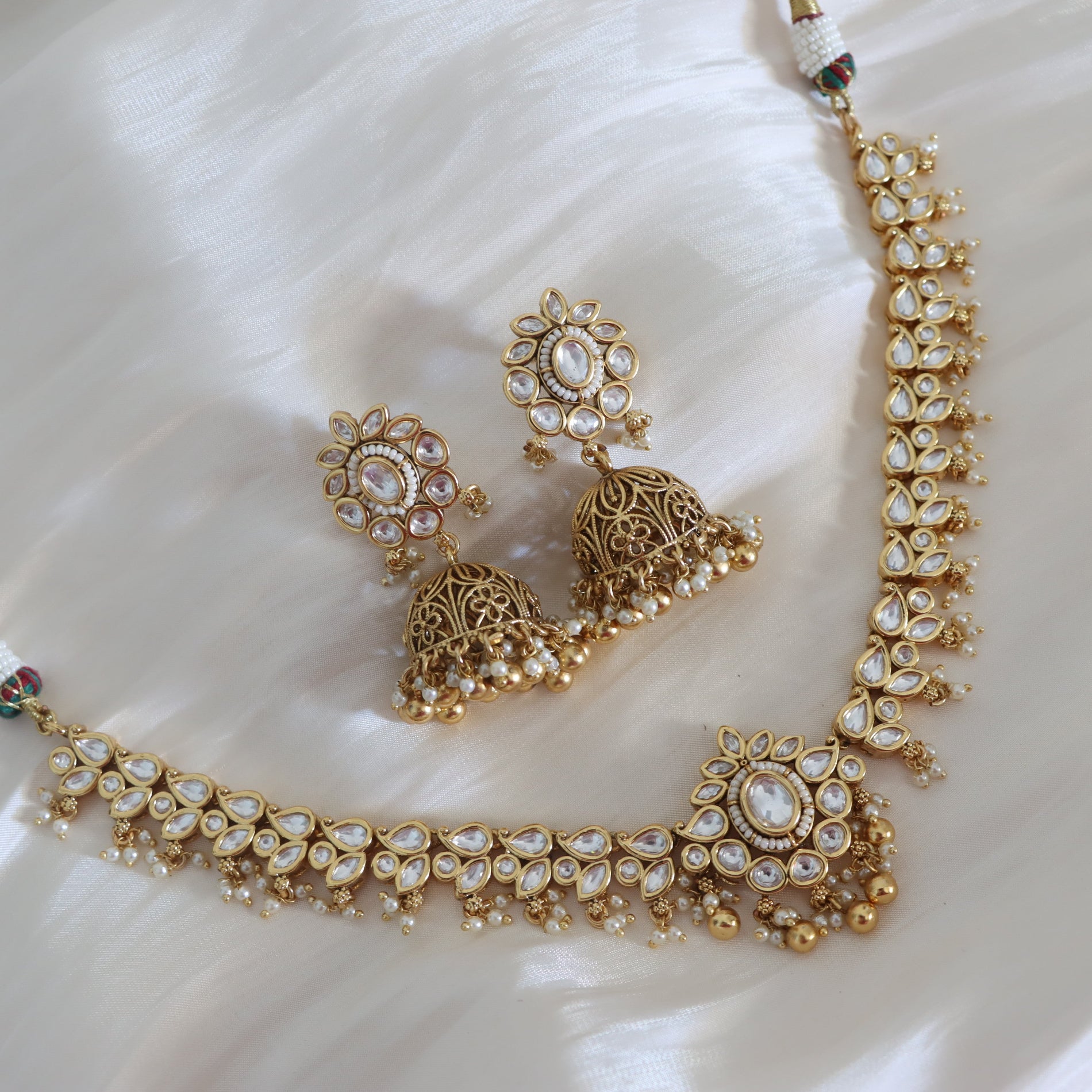 Gold necklace and earrings set on a white fabric background