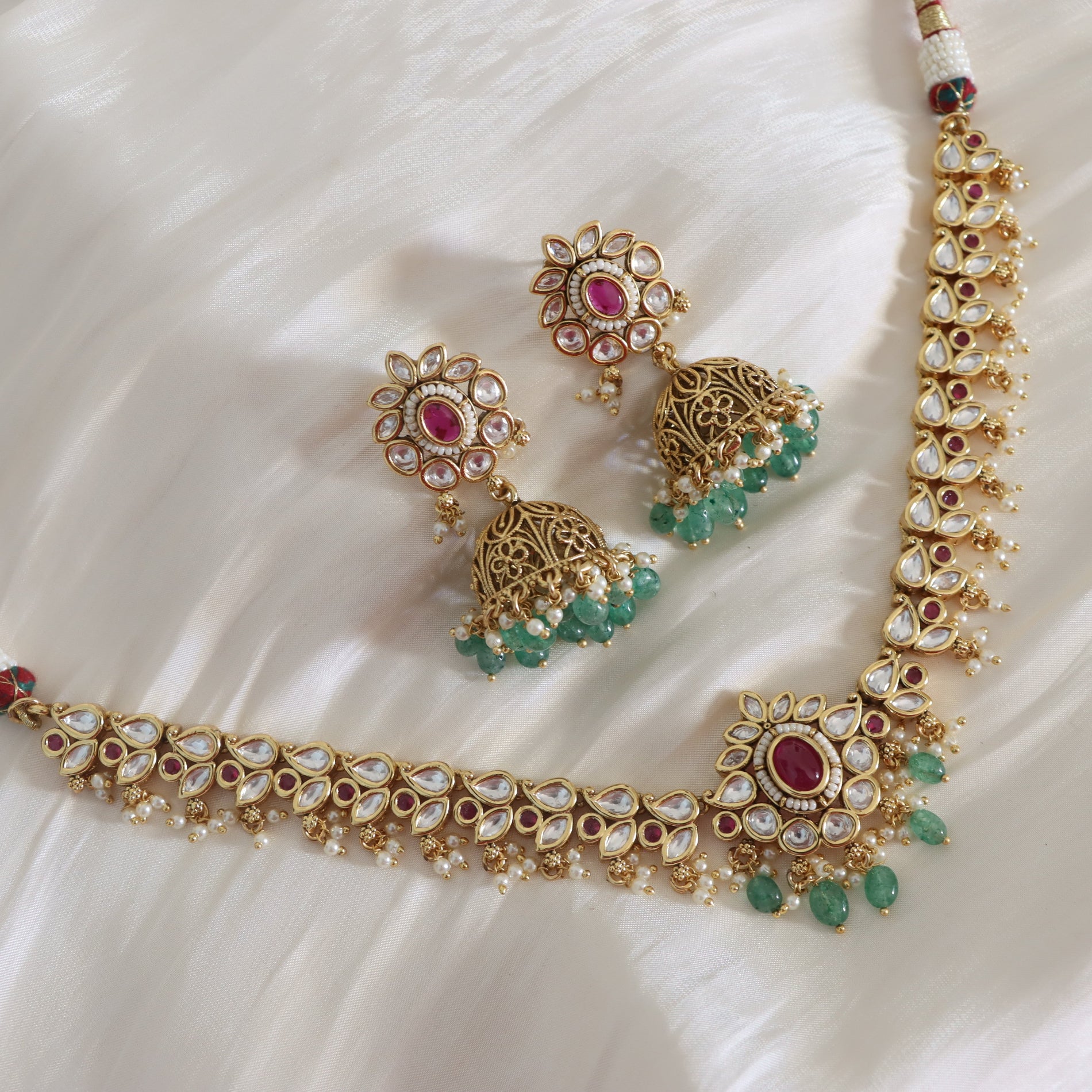 Gold jewelry set with emeralds and rubies on a white fabric background