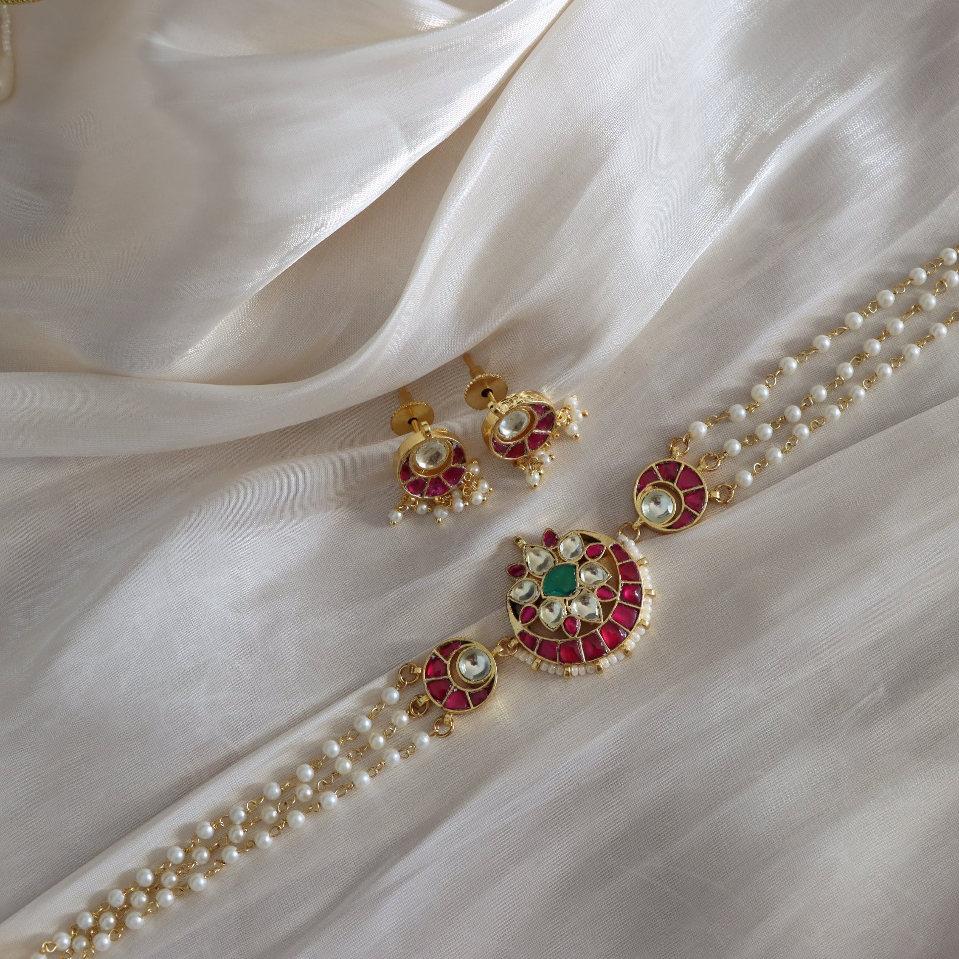 Decorative necklace and earrings on a white fabric background