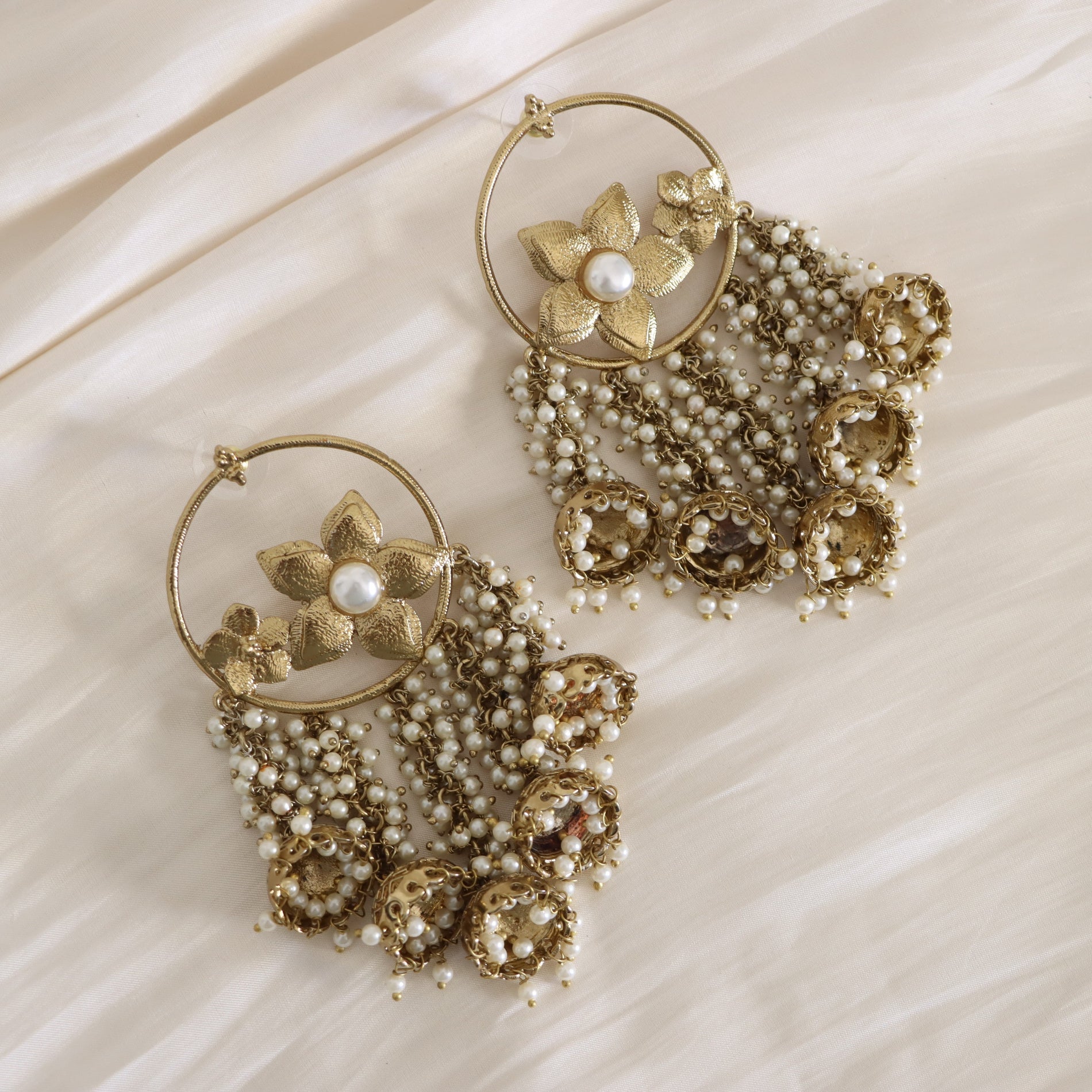 Gold and pearl earrings on a beige fabric background