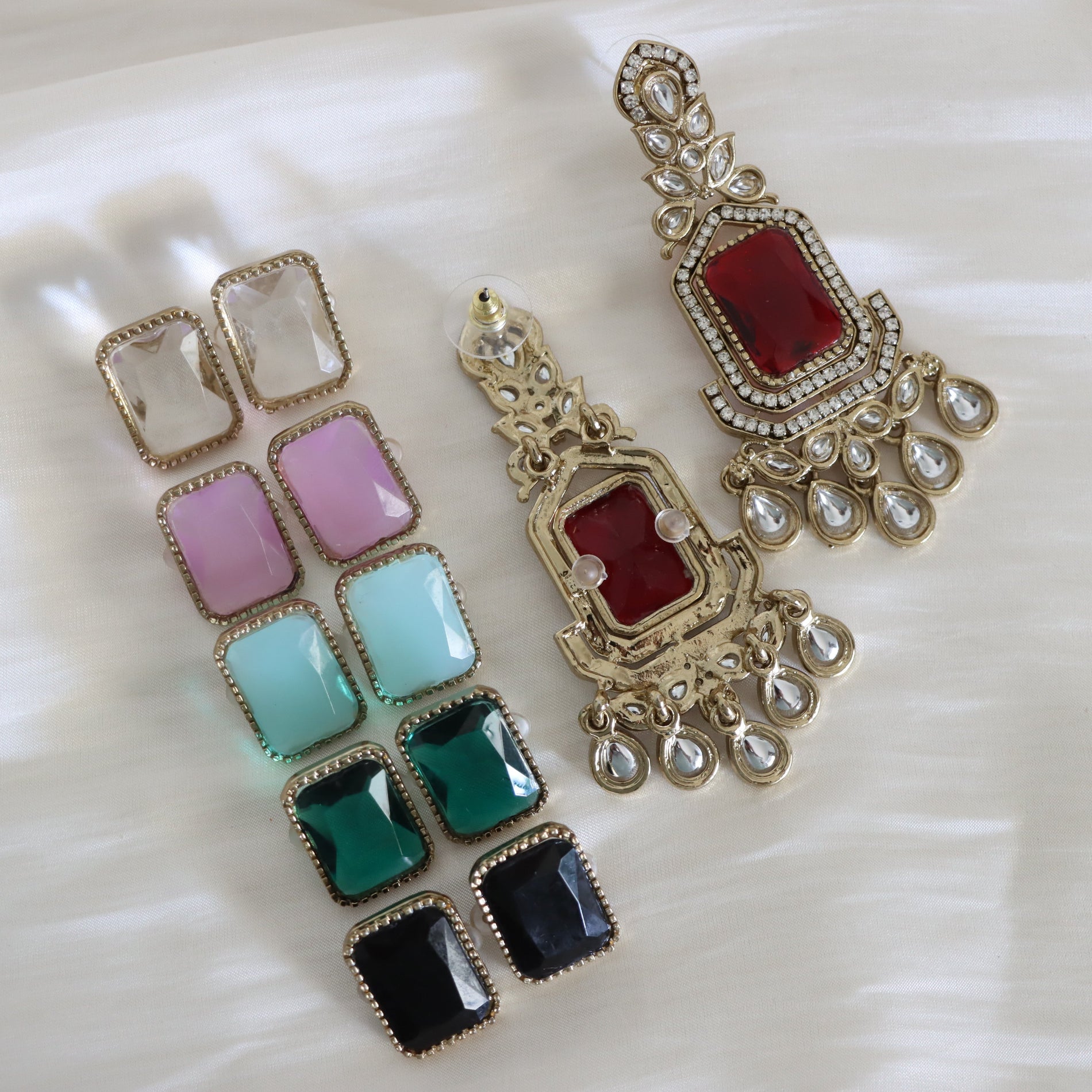 Colorful square gemstone earrings with gold accents on a white surface