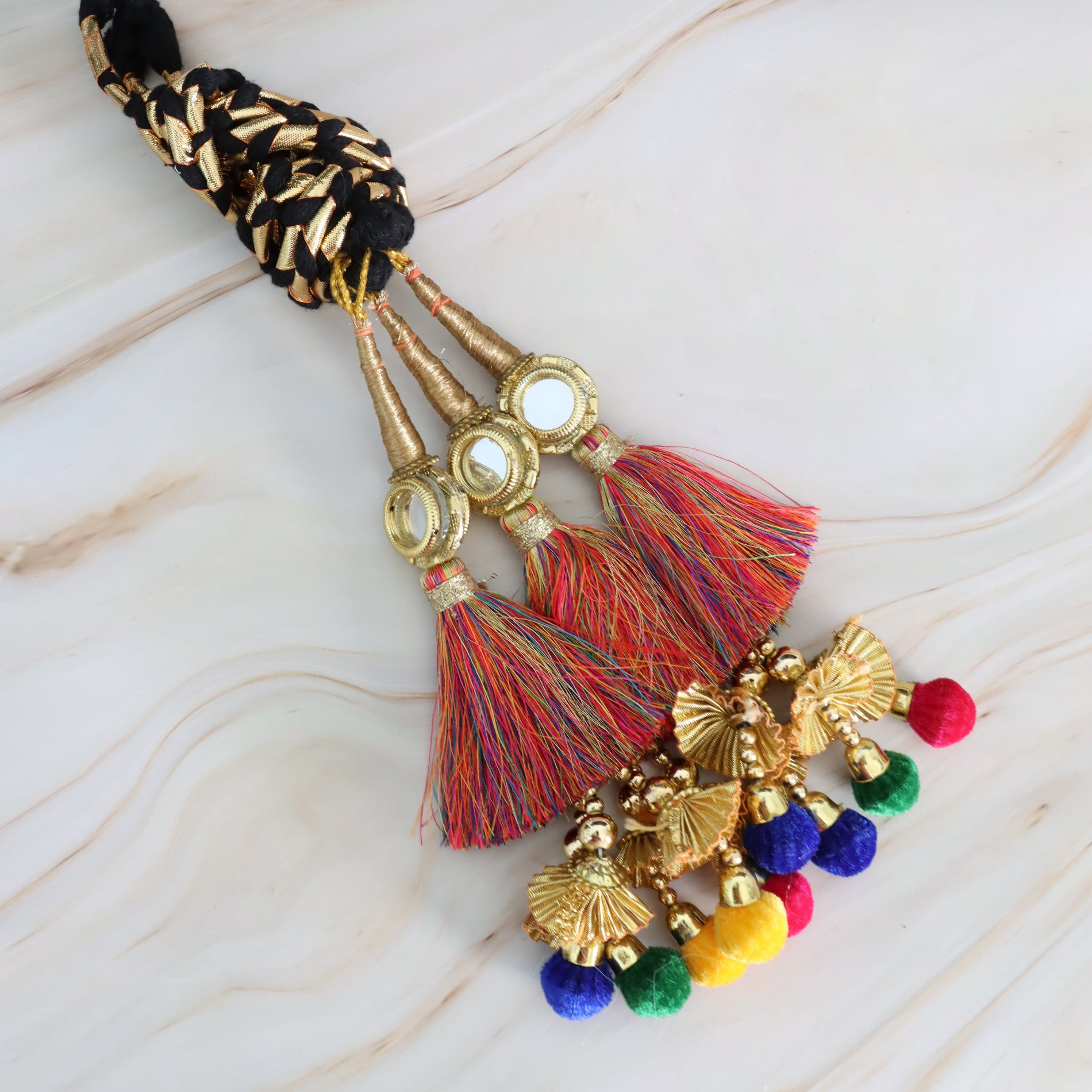 Decorative parandi with tassels and colorful beads on a marble surface