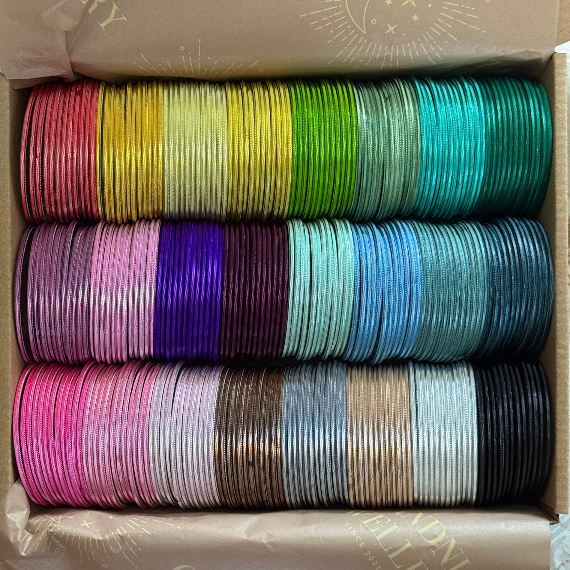 Box containing multiple rolls of colorful bangles in various colors.
