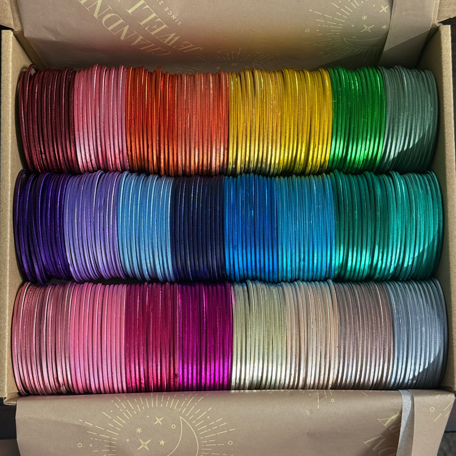 Box containing colorful spools of bangles in various colours.