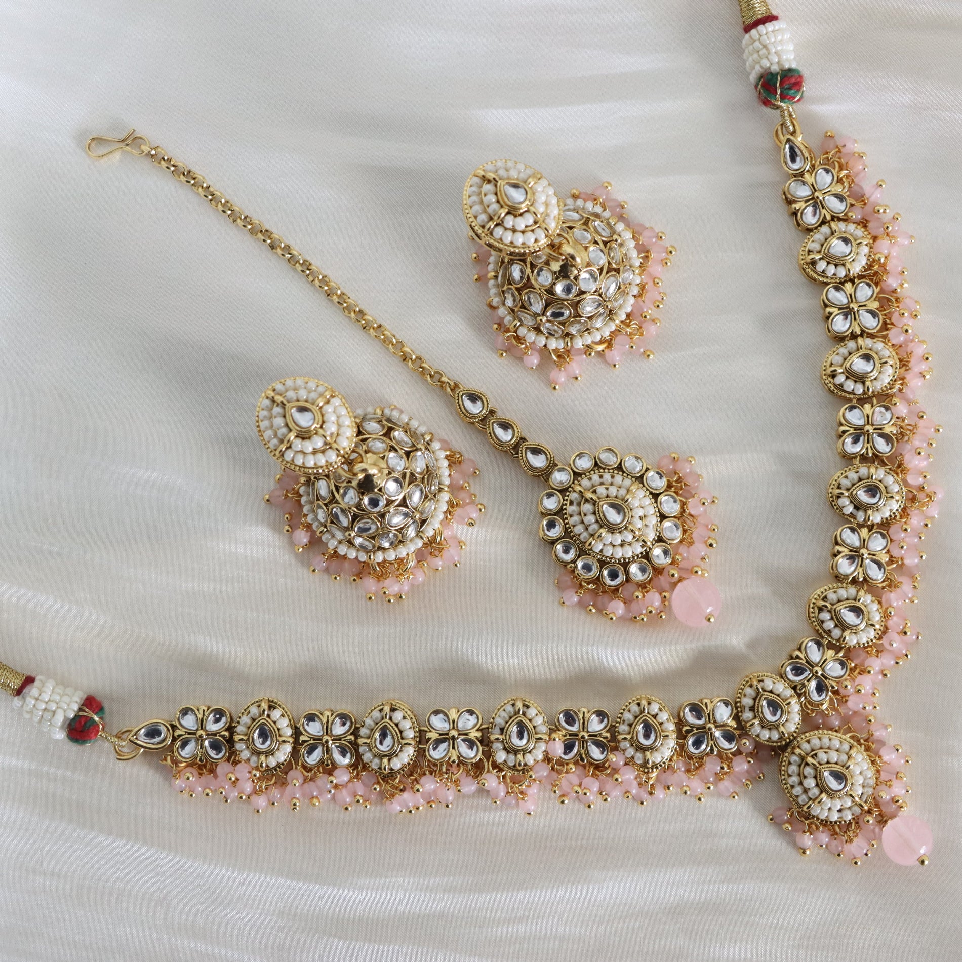 Ornate jewelry set with necklace, earrings, and bracelet on a white background