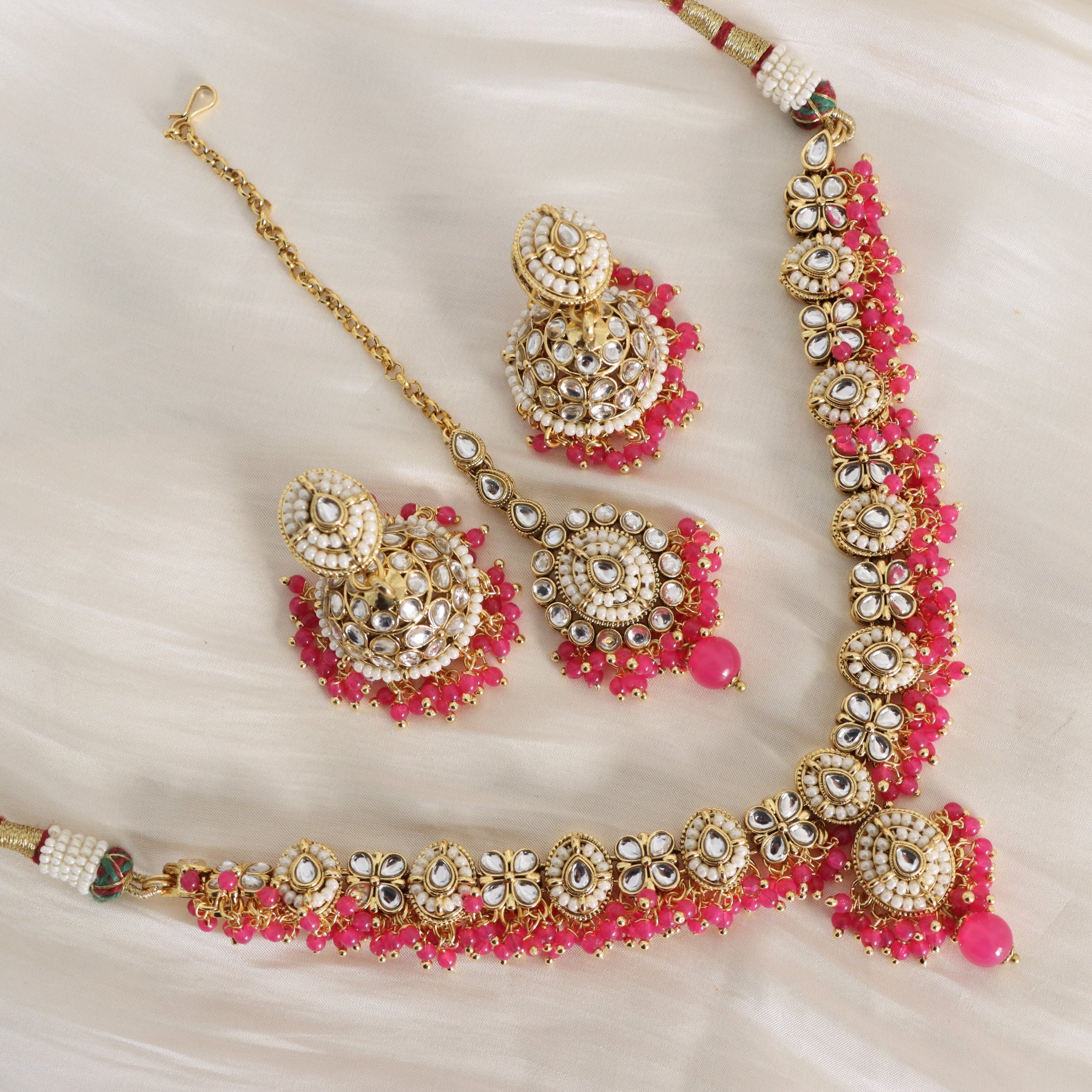 Ornate jewelry set with pink stones on a white background