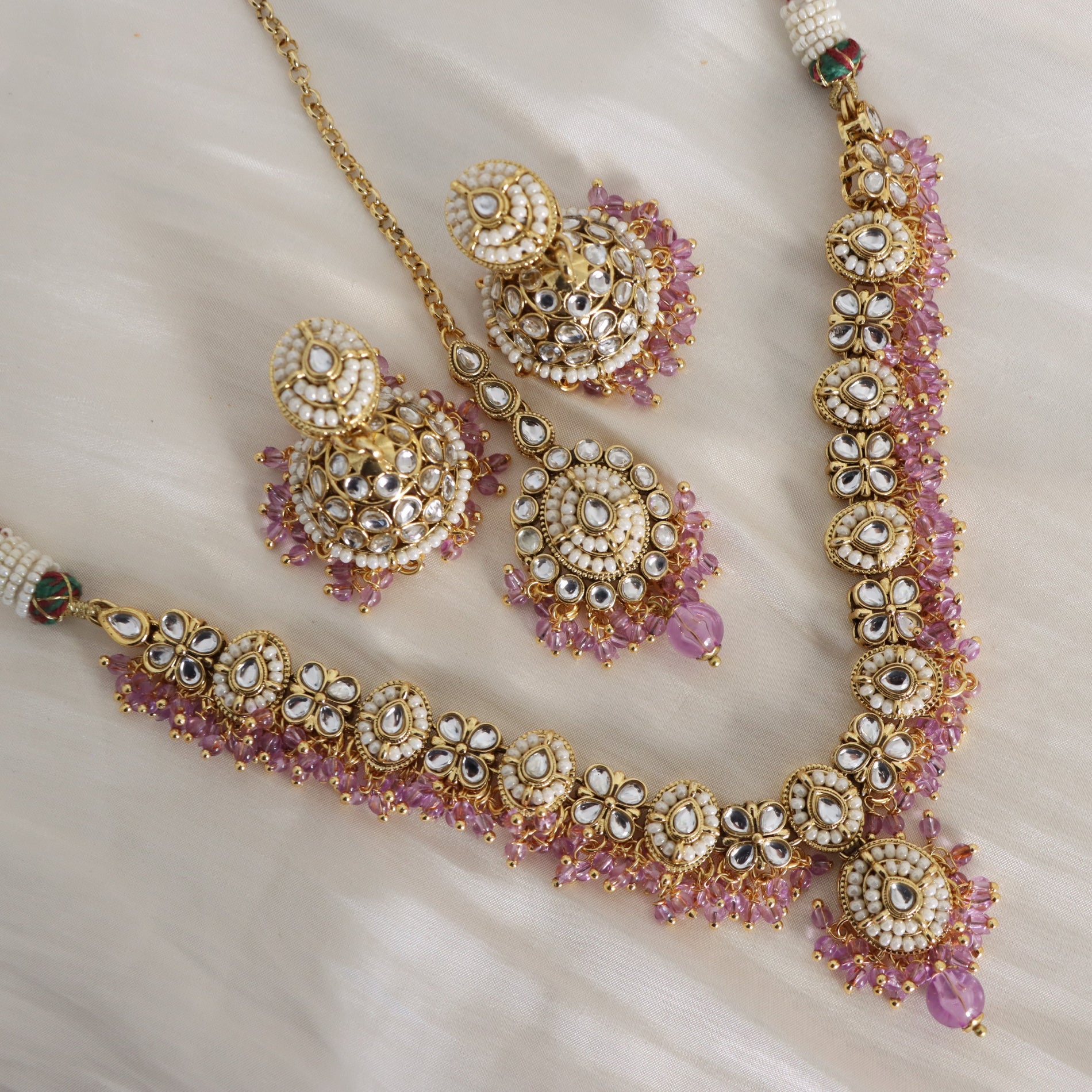 Ornate jewelry set with pink gemstones on a soft fabric background