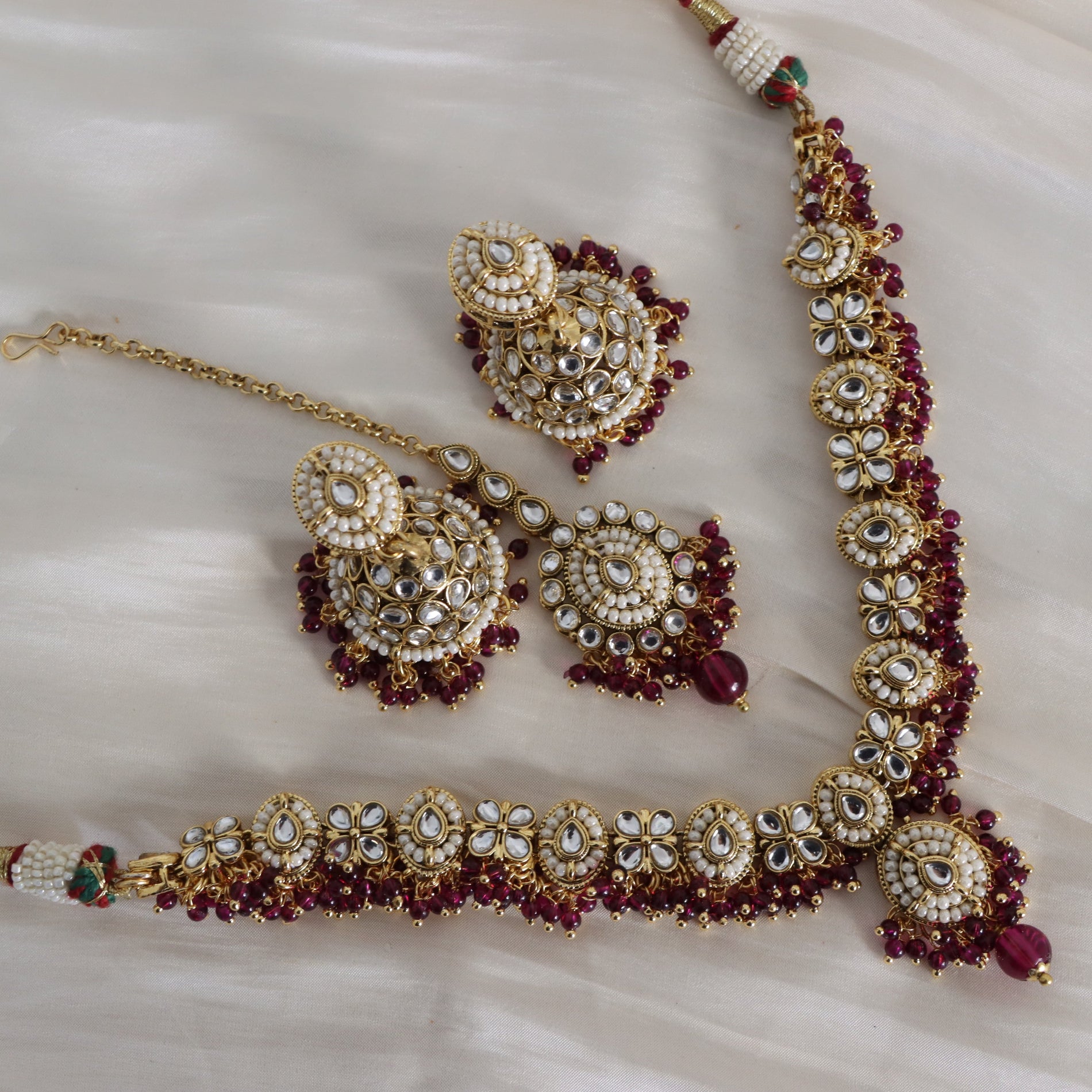 Ornate gold and red jewelry set on a white fabric background