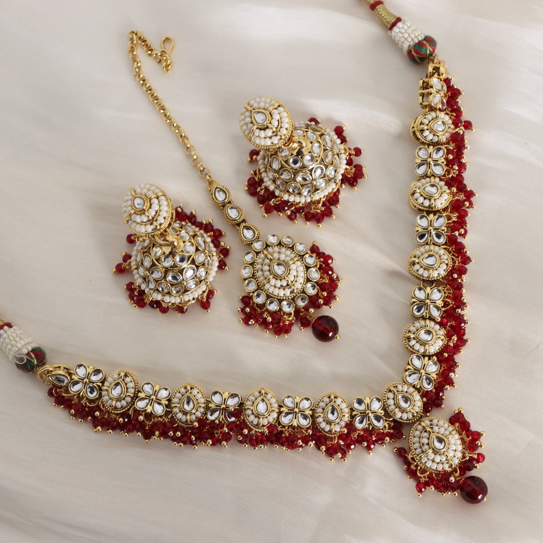 Ornate gold and red jewelry set on a white fabric background