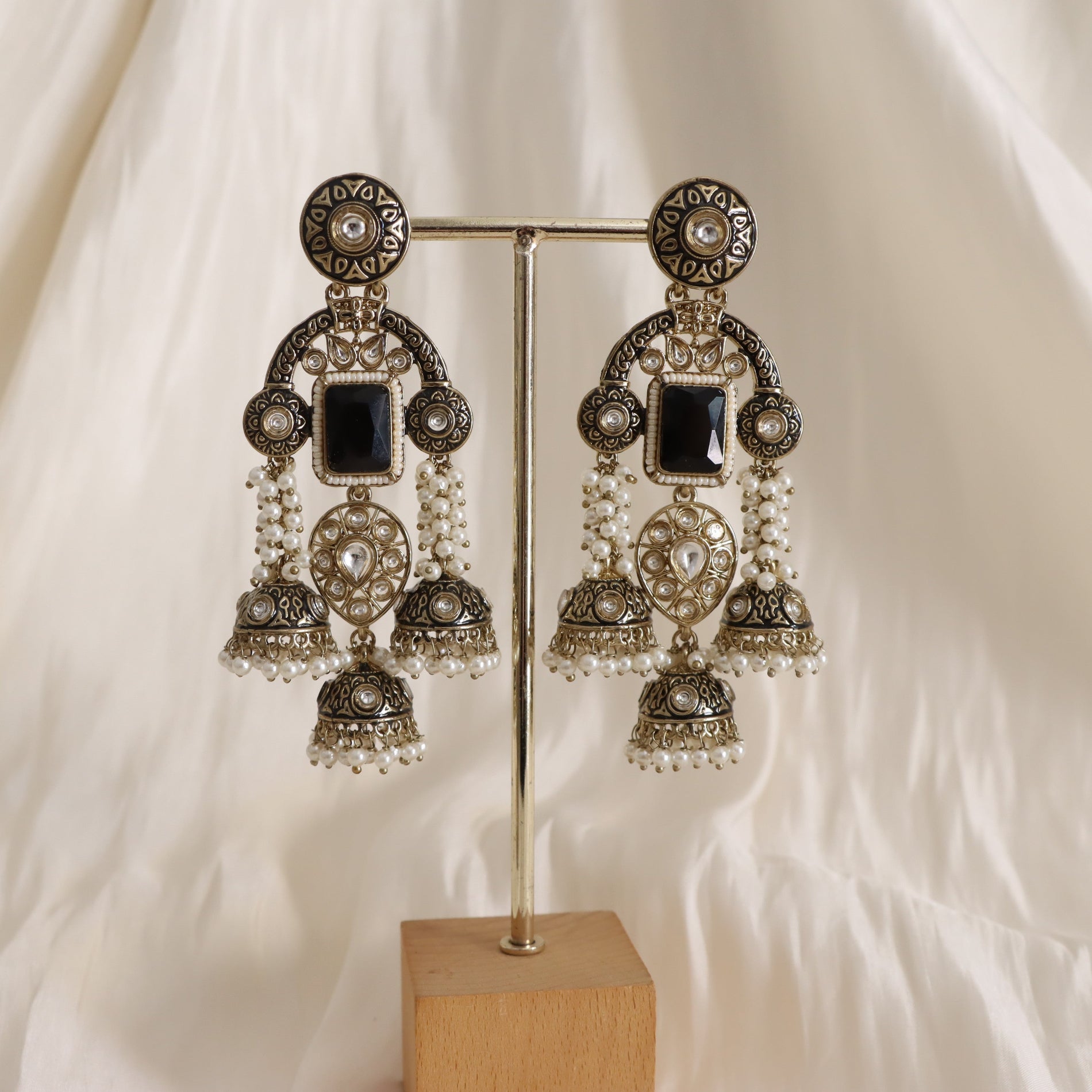 Ornate earrings on a stand against a white background