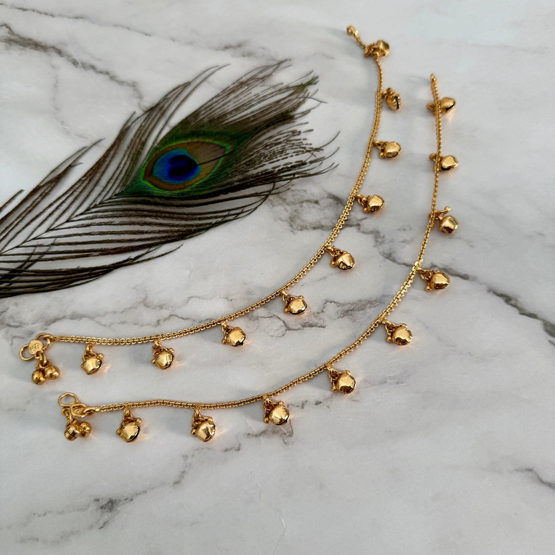 Gold anklet with bells on a marble surface