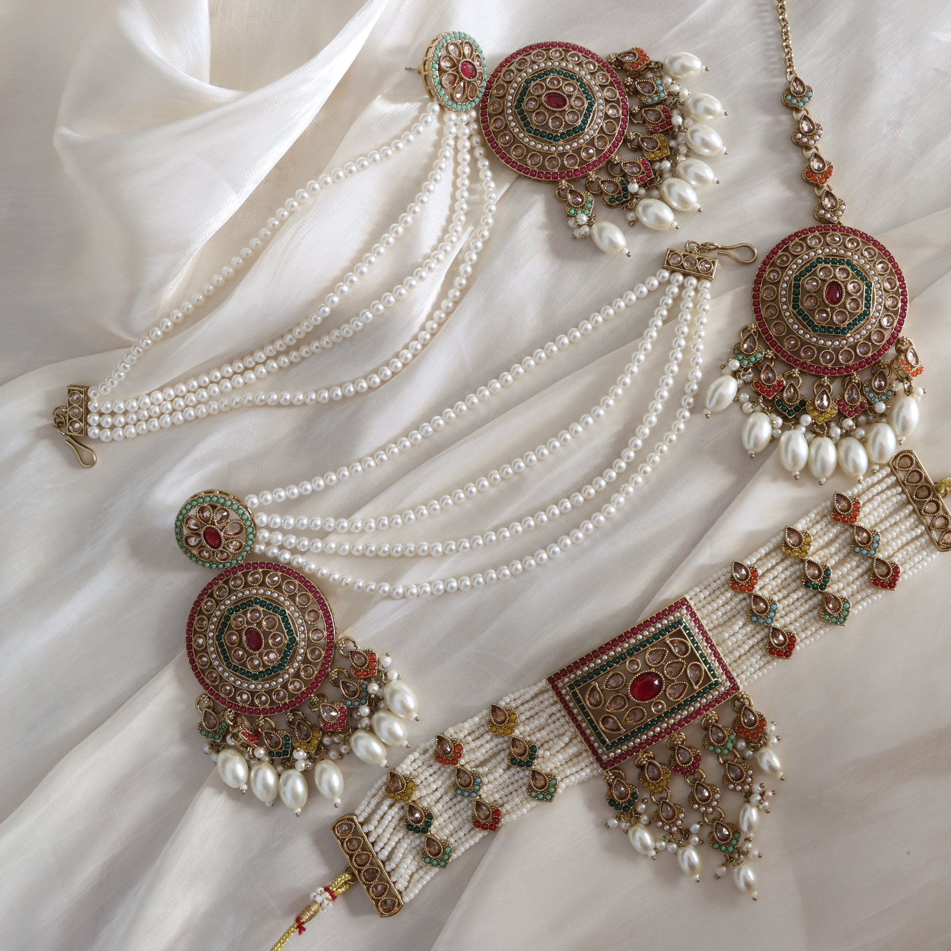 Ornate jewelry set with pearls on a white fabric background