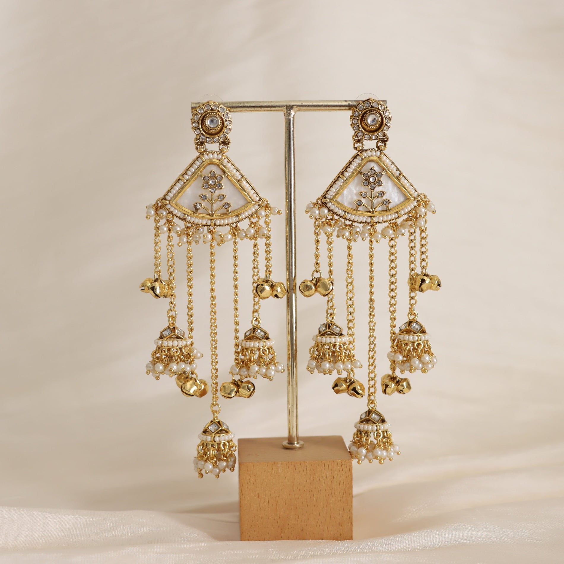 Gold earrings with intricate designs on a beige background