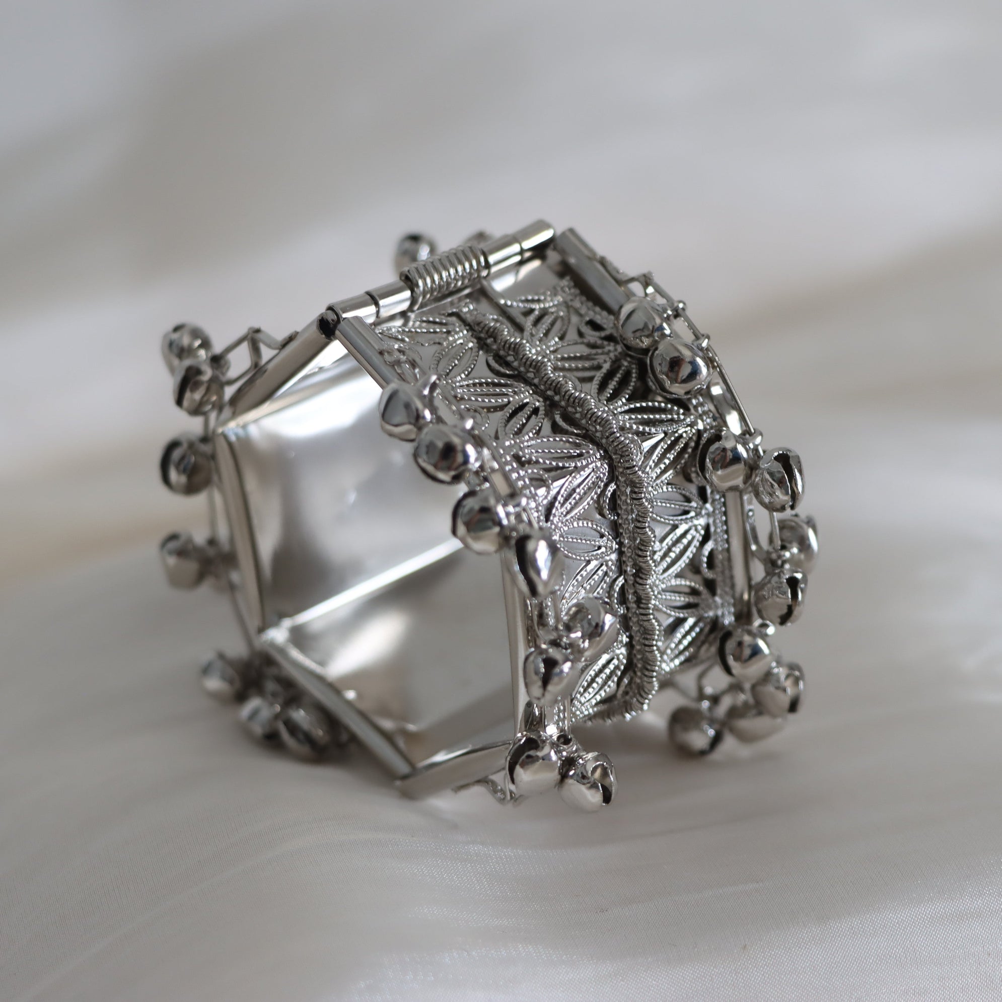 Silver bracelet with intricate designs on a white background