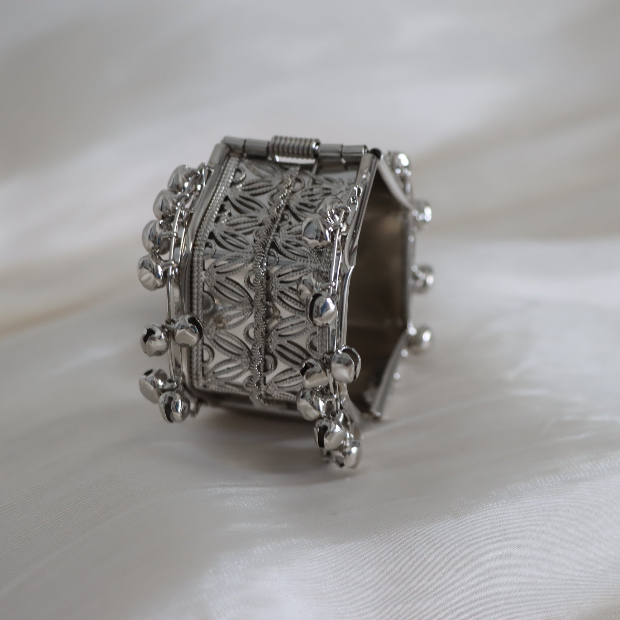 Silver bracelet with intricate design on a white background
