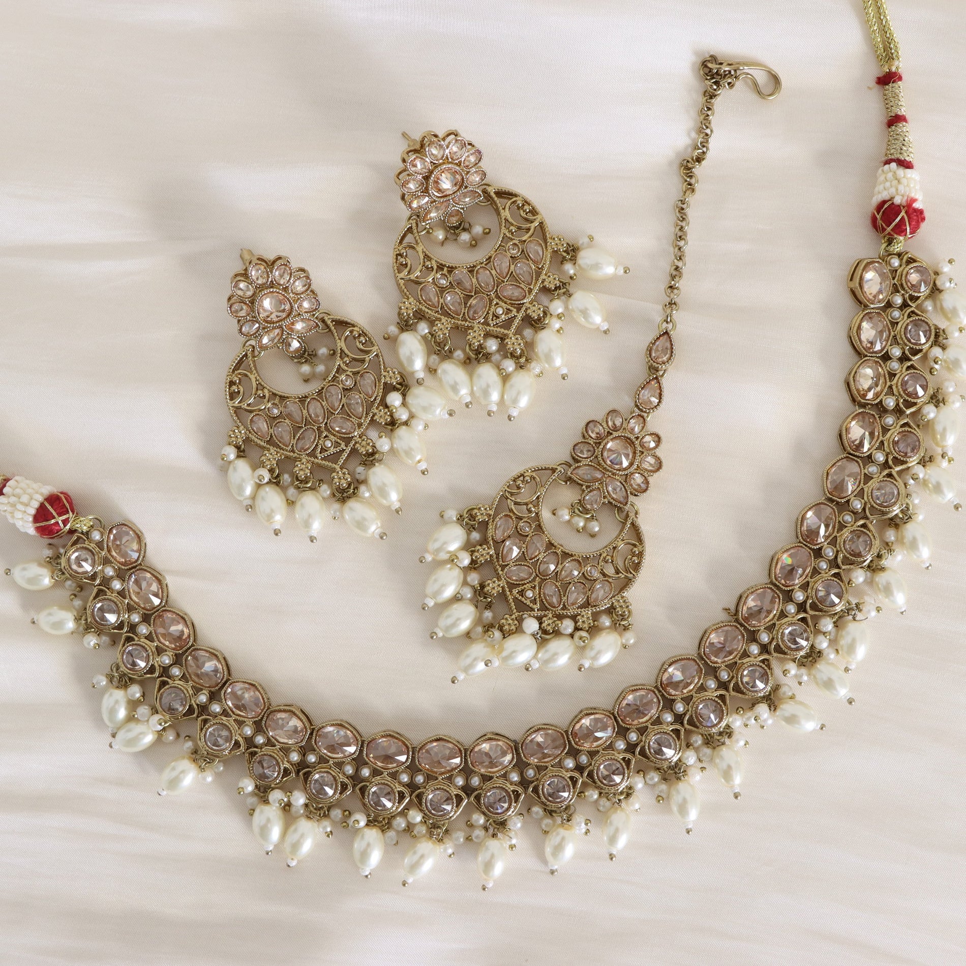 Ornate necklace and earrings set with pearls on a white background