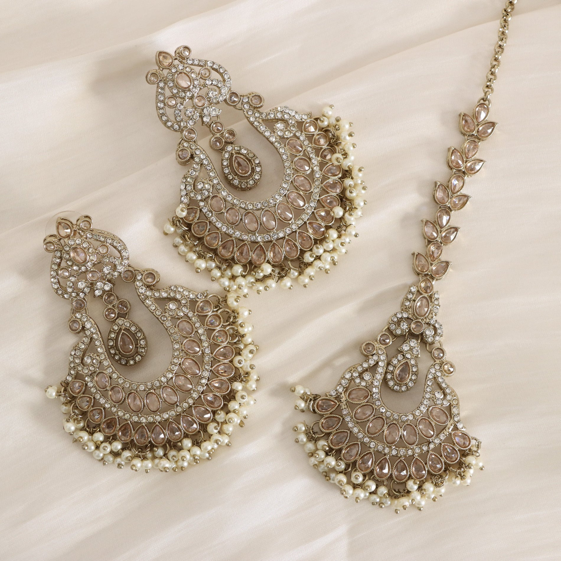 Ornate jewelry set with earrings and a necklace on a light background