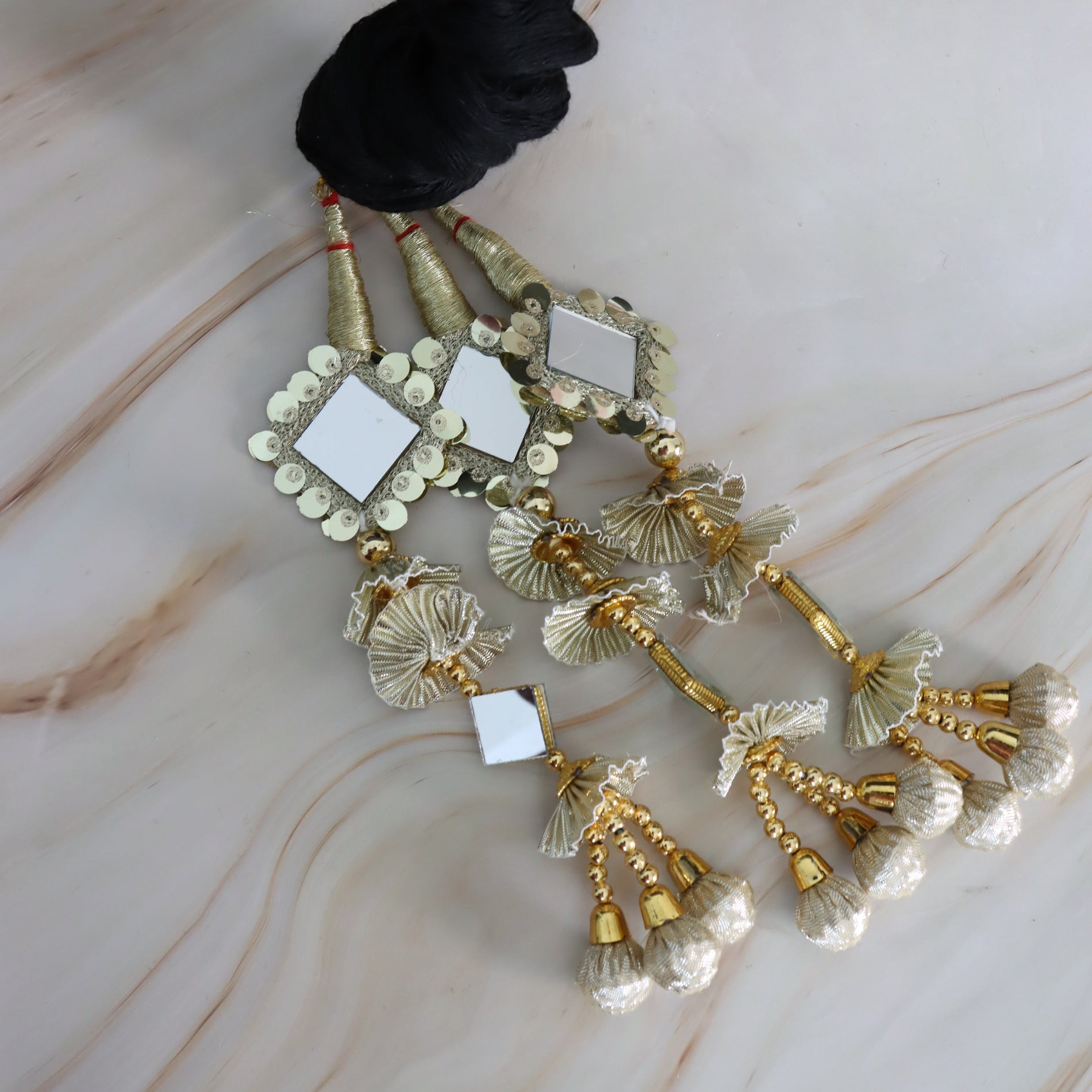 Decorative hair accessory with gold and silver elements on a marble surface