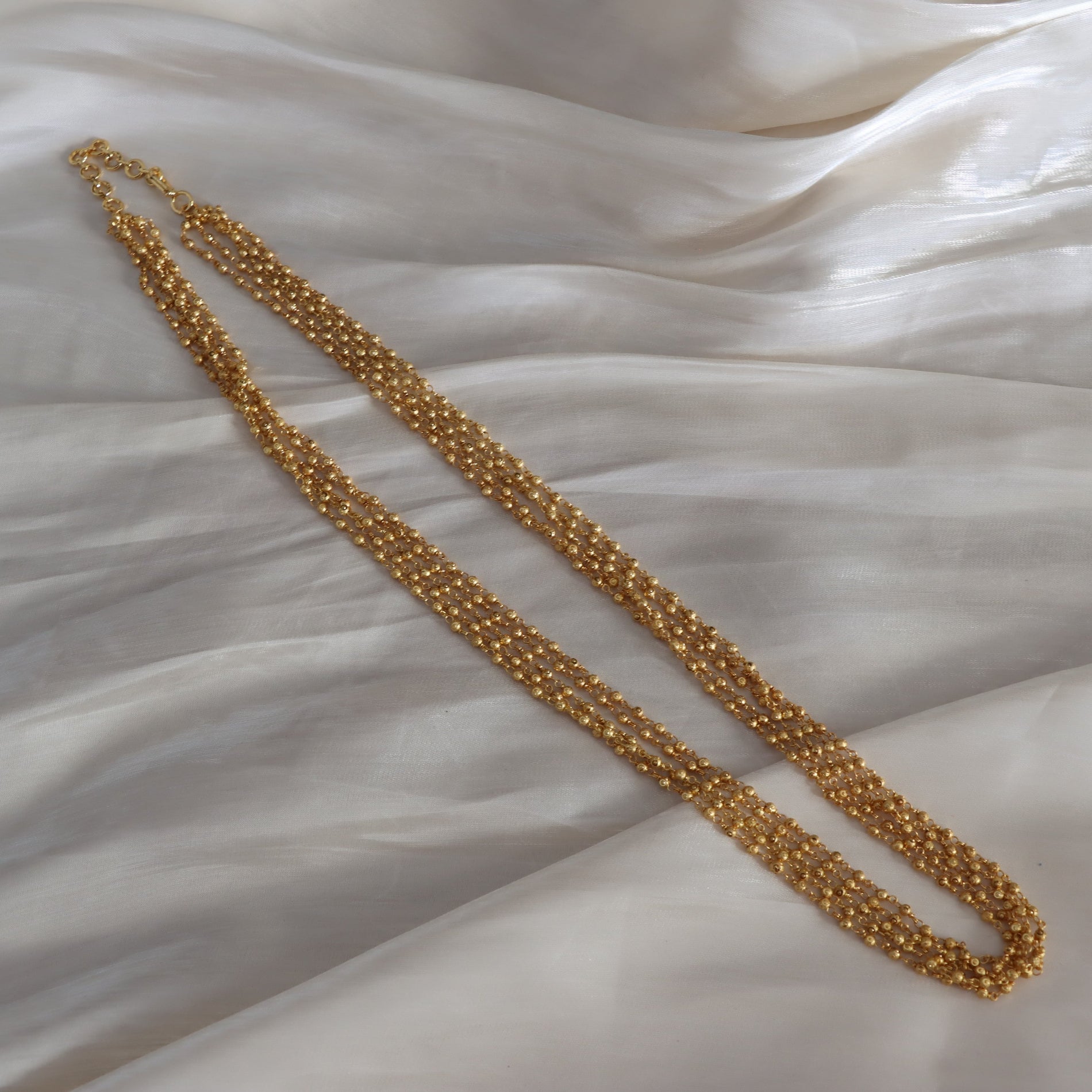 Gold necklace on a textured white fabric background