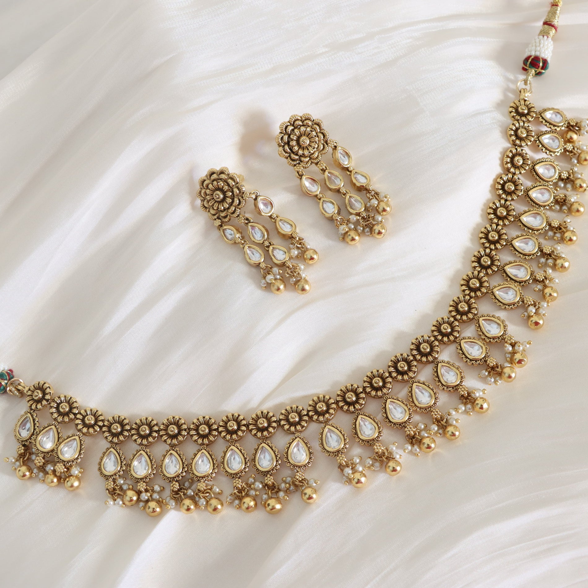 Gold necklace and earrings on a white fabric background