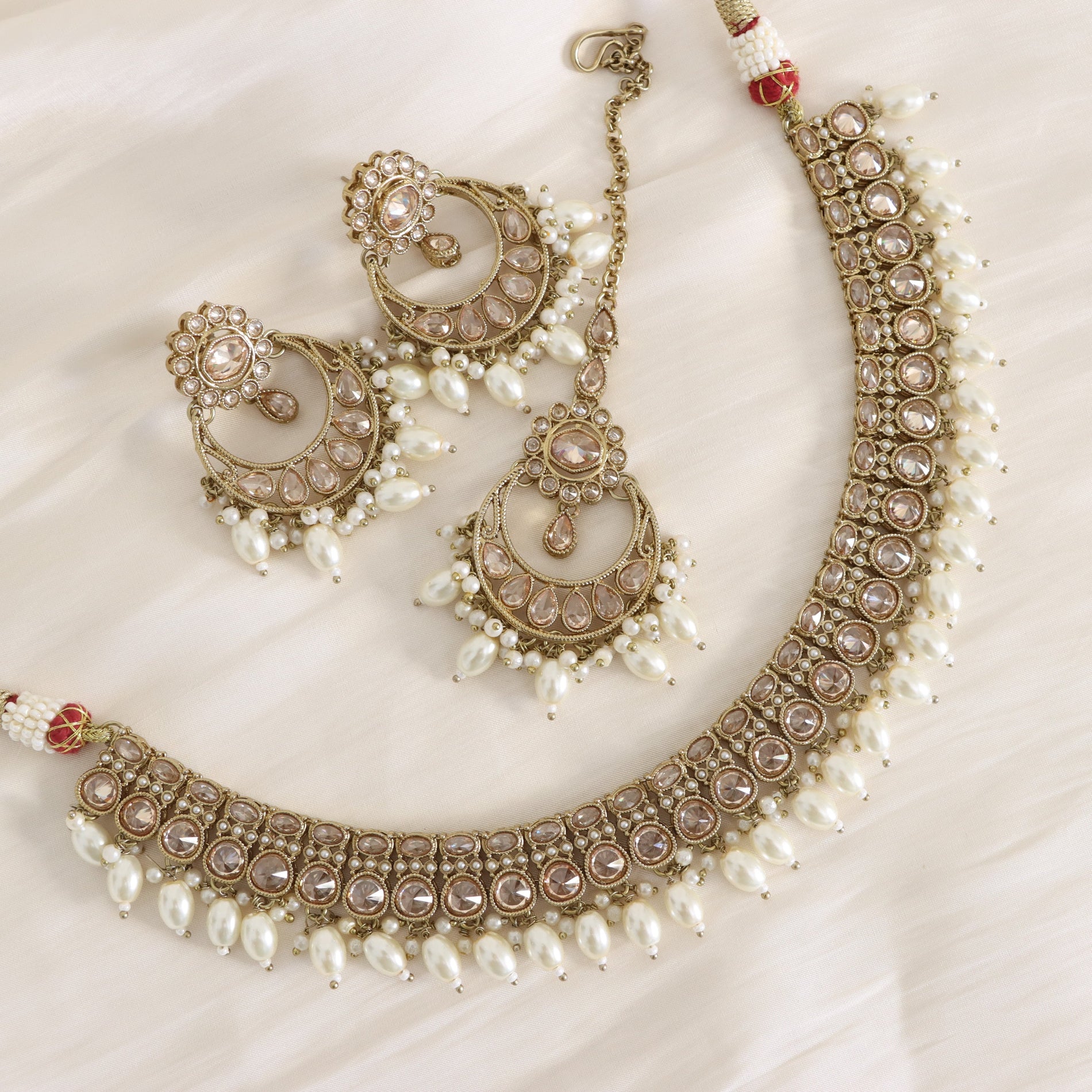 Ornate necklace and earrings set with pearls on a white background