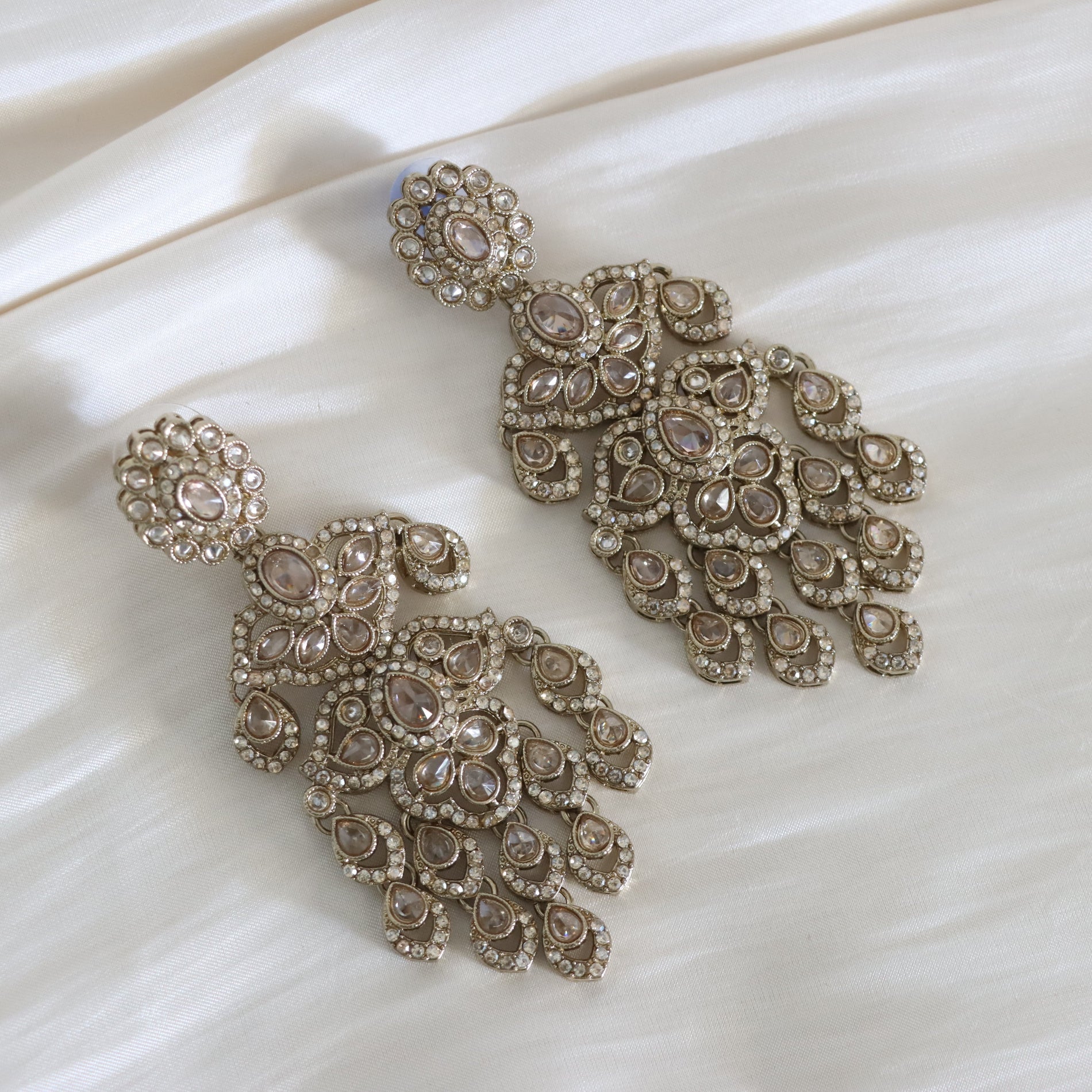 Pair of ornate earrings on a textured white surface