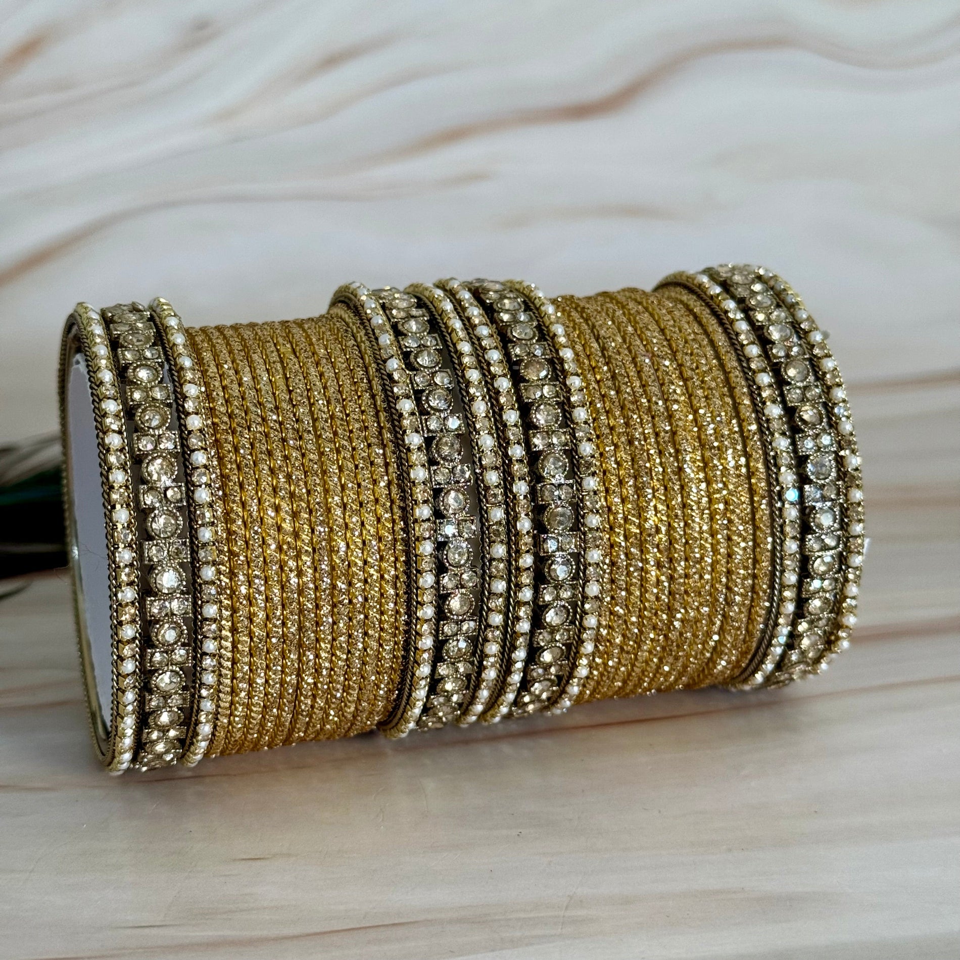 Set of golden bangles on a light wooden surface