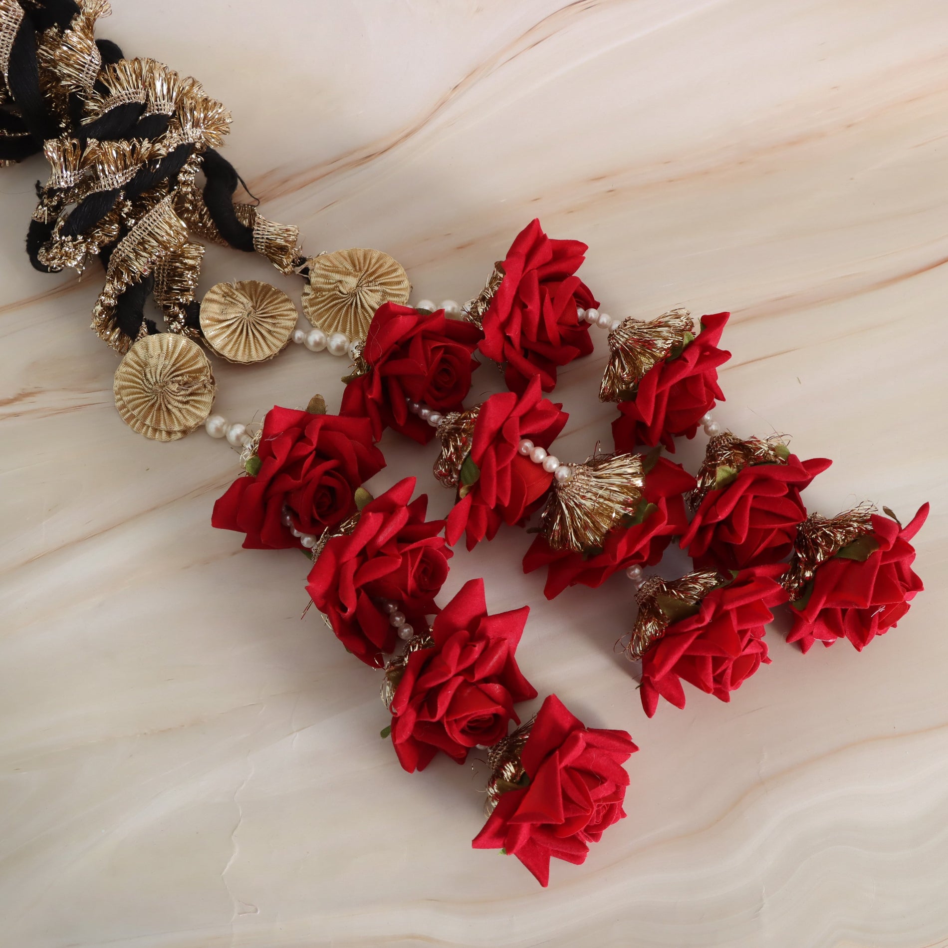 Decorative headband with red flowers and gold and black accents on a light wooden surface