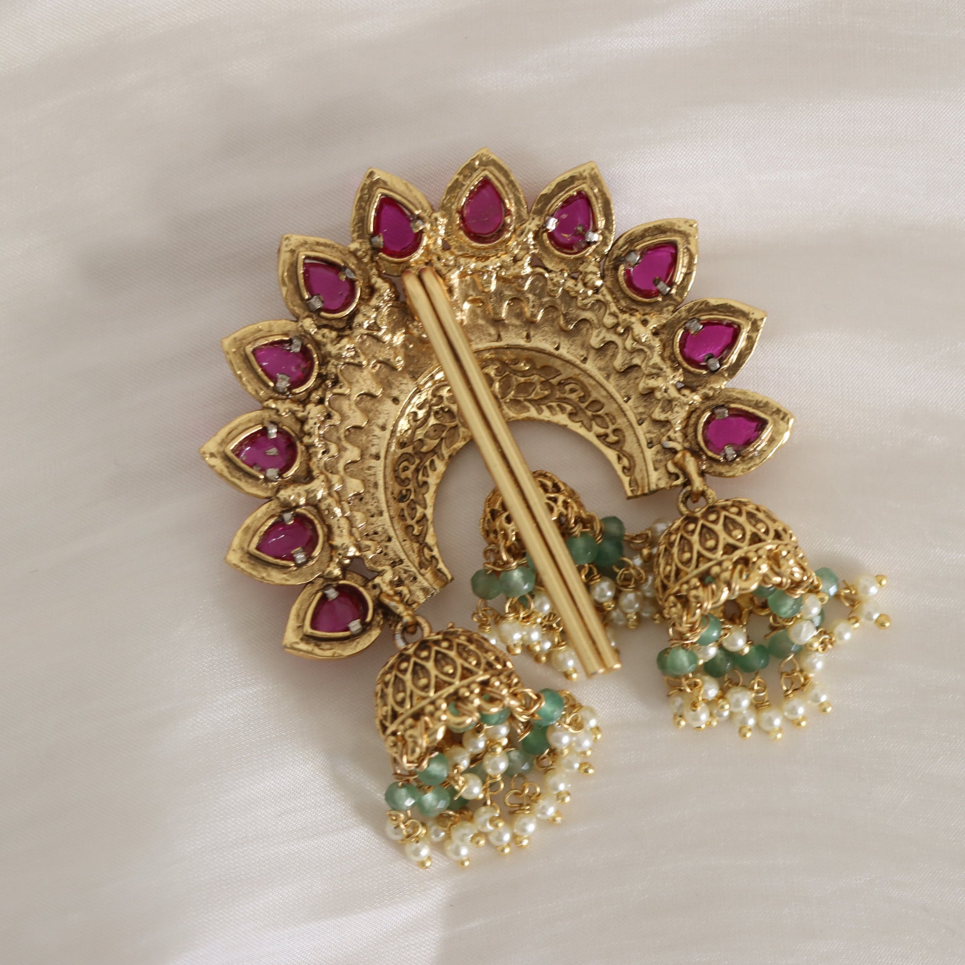 Gold and pink gemstone brooch with pearl and green bead details on a white background