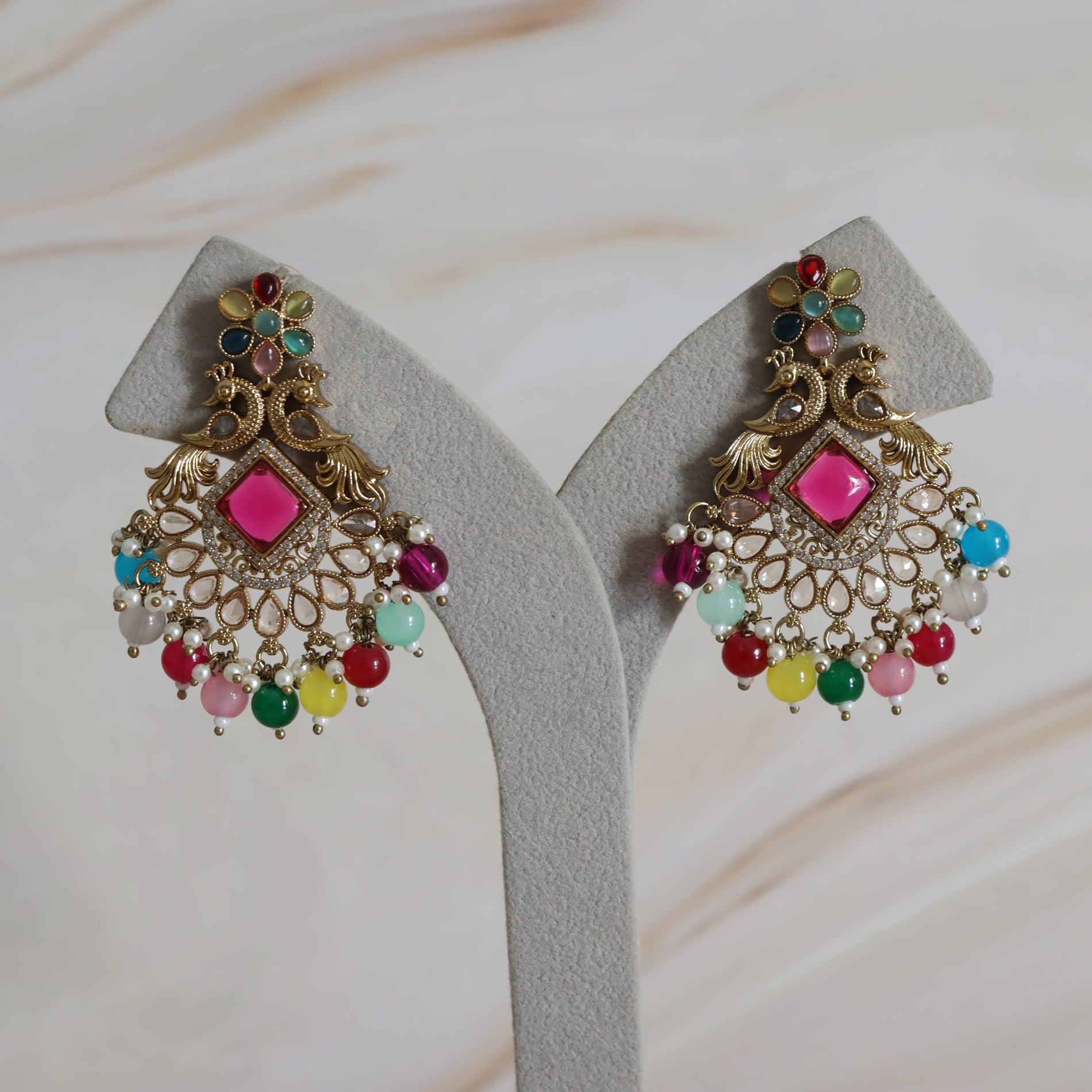 Decorative earrings with colorful beads on a white stand.