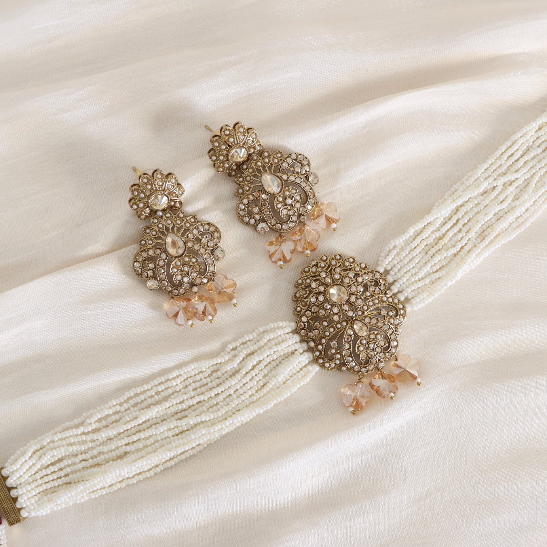 Ornate earrings with beaded strands on a satin surface
