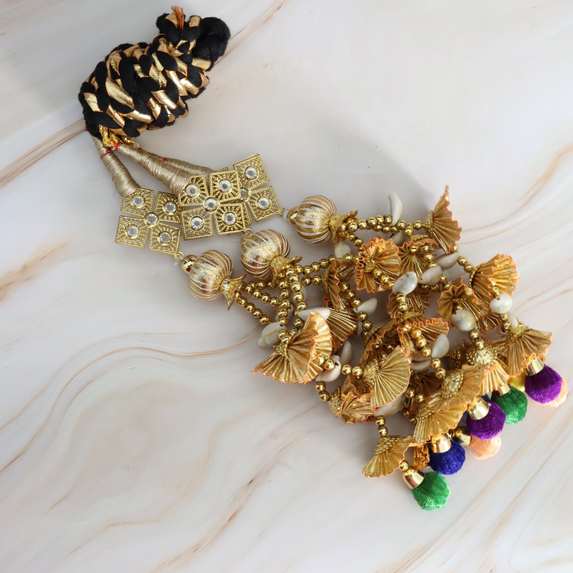 Decorative hair accessory with gold and black elements on a marble surface