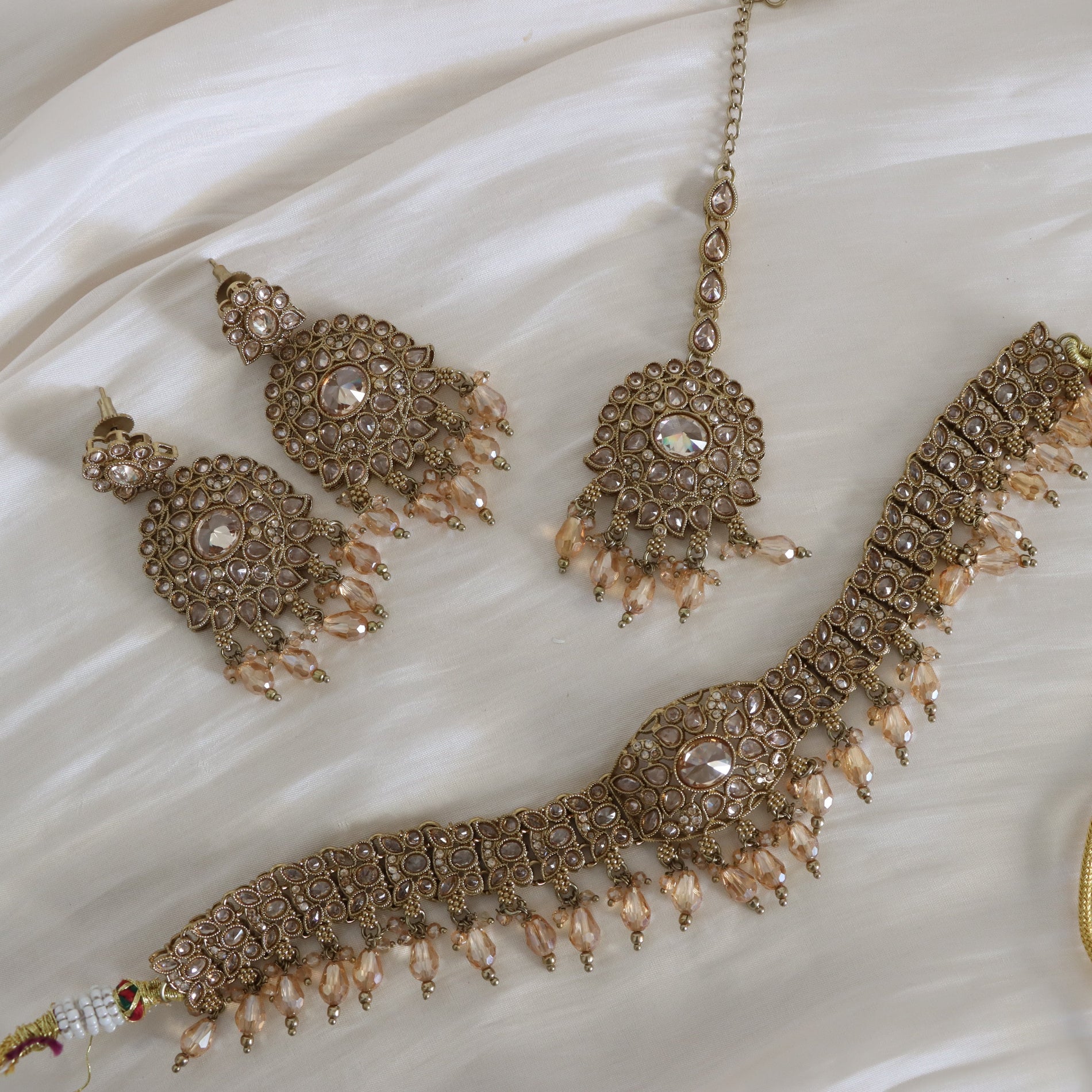 Ornate jewelry set with necklace, earrings, and bracelet on a white fabric background