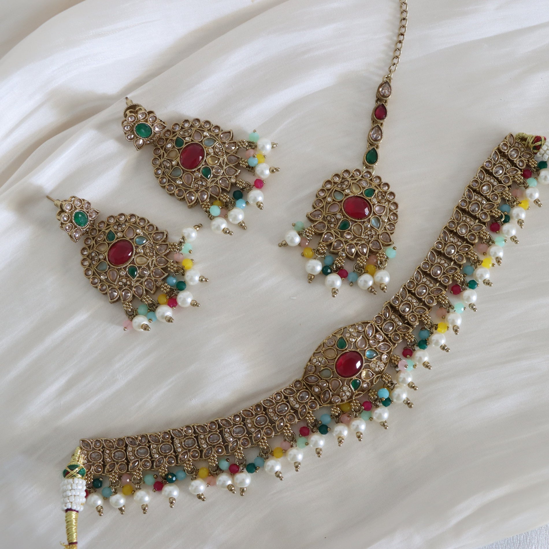 Ornate jewelry set with necklaces and earrings on a white fabric background