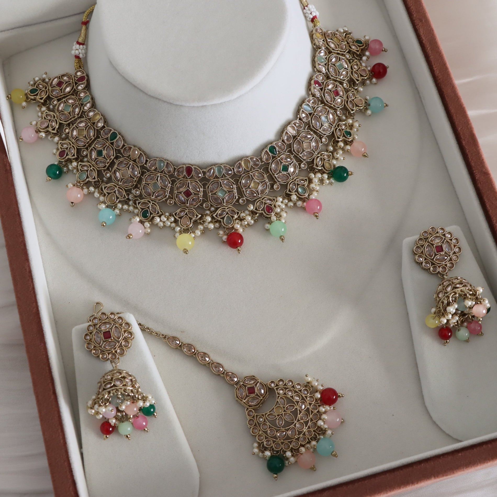 Ornate necklace with colorful beads on a white stand